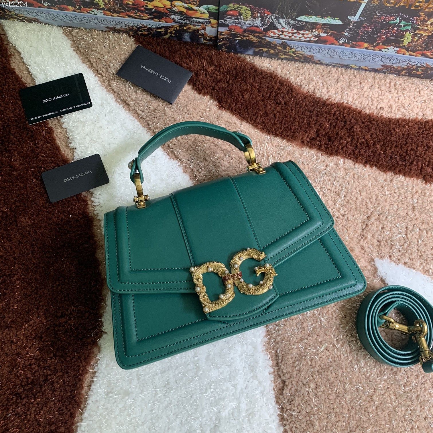 杜嘉班纳 【Dolce Gabbana 杜嘉班纳】顶级原单 独特之处，彰显在红色卷轴上构成“Amore”的巴洛克式风格❤️配装饰有珍珠和连接 DG 两个字母的“Amore”字母卷轴的镀复古黄铜金属 DG 徽标，隐藏式按压扣开合，顶部小牛皮把手配两侧珍珠徽标细节，可调节、可拆卸小牛皮肩带，内部撞色纳帕小牛皮结构，配拉链口袋和品牌滑索以及有中间分隔物的两个隔间 ➰细腻手工制造 ??
