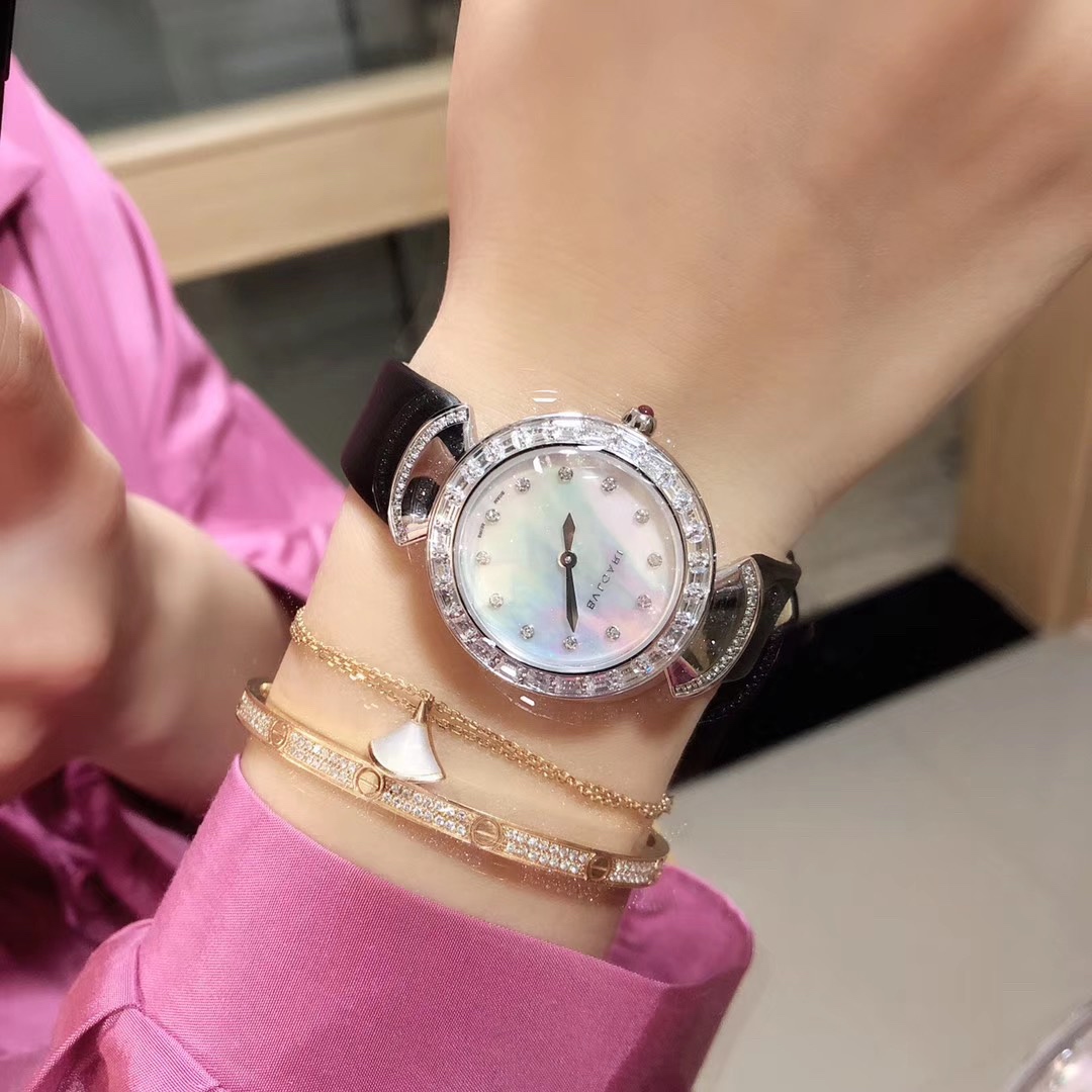 Bvlgari 宝格丽圈口镶石由全手工镶施华洛钻打造而成 把头微镶着一粒红宝石 表盘有两种：天然珍珠贝壳面