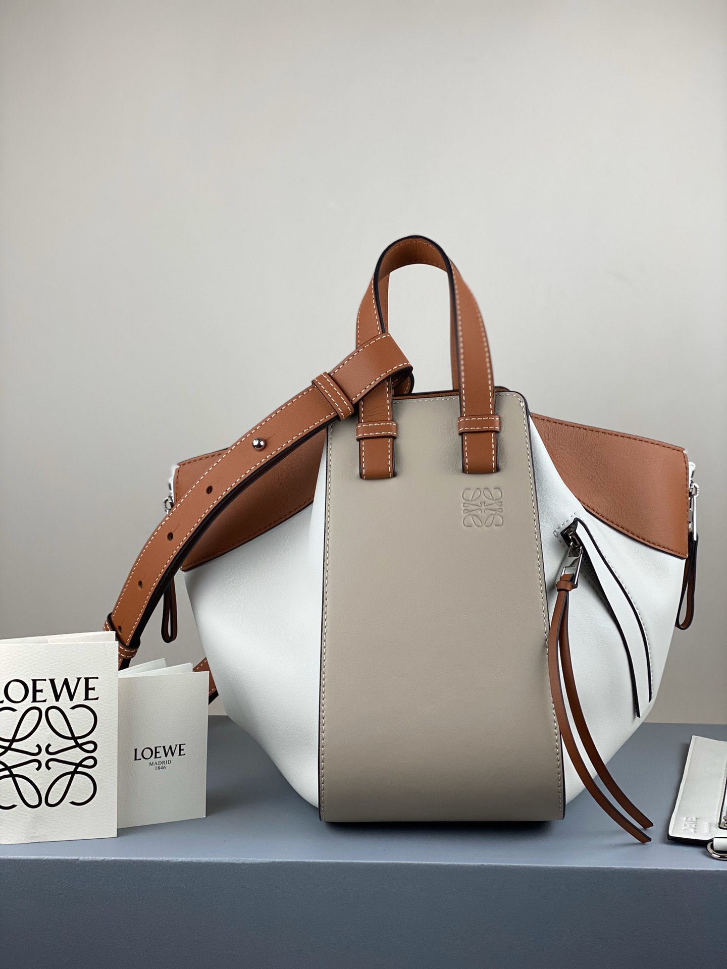 Model 3047100 White/Brown Loe❤we hammock, the latest version synchronized with the official store. Small size 29*26*14cm, large capacity, with a foldable zipper design for easy transformation. Can fit a MacBook and A4 notebook, with small pockets on both sides for cards and essentials. If you need more space, unzip for extra storage. Perfect for work and travel, versatile with various outfits. Made of Spanish calf leather, top-quality hardware, and exquisite craftsmanship. image 1