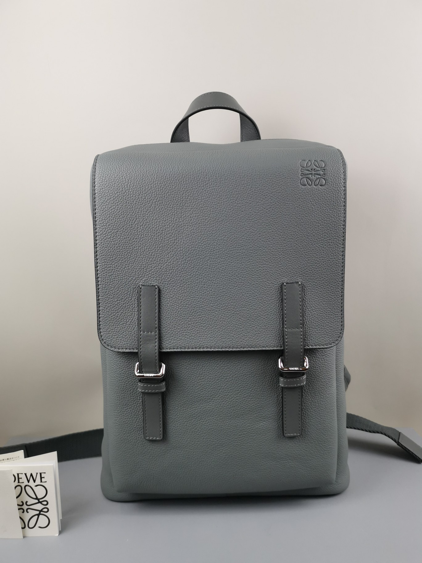 Soft grain leather military backpack in 3 colors, size 39-28.5-11, model 330125. The Military Backpack is spacious and versatile, featuring a main compartment and an additional compartment under a fold-over flap, secured with magnetic and extra buckle closures. The padded shoulder straps are adjustable with metal sliders. Can be worn as a backpack, shoulder bag, or carried by the top handle. Includes a large internal pocket for a laptop. Lined with herringbone cotton canvas. Anagram embossing. image 1