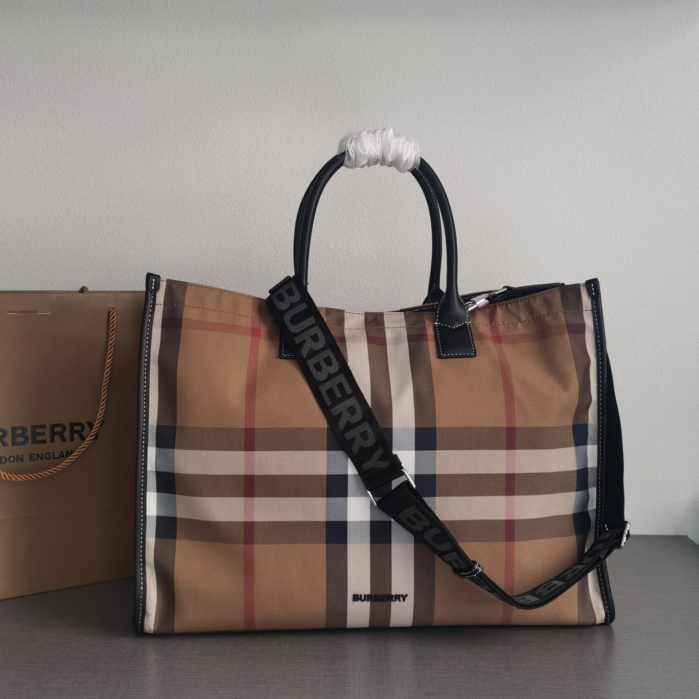 Burberry's large cotton plaid casual tote style "The Belt" is made of cotton canvas and flexible leather. It has a strap inspired by the brand's