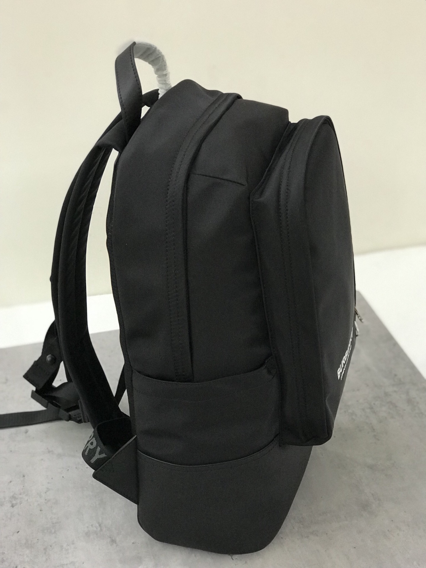 The Burberry backpack is crafted from ECONYL fabric and has a topstitched leather base. It has multiple pockets and a laptop compartment, creatin