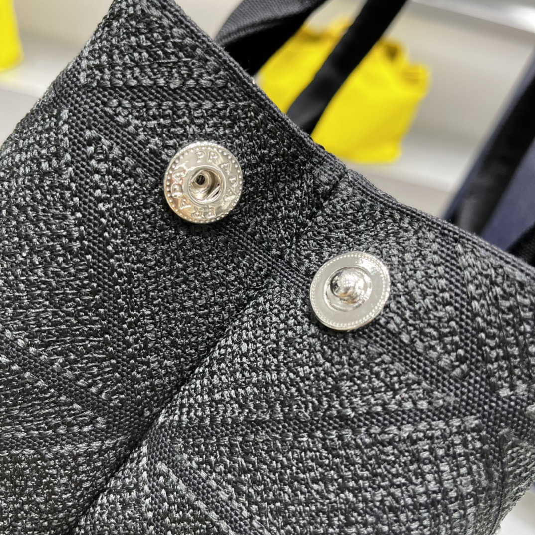 Prada 刺绣图案成为标志性 Prad#标志的表现形式 为这款棉质托特包打造通体质感 配饰配有可拆卸肩带和皮革手柄