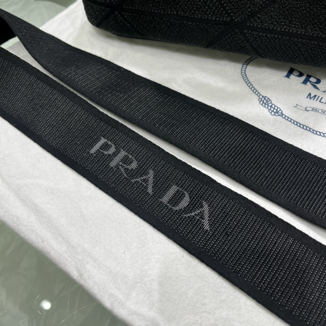 Prada 刺绣图案成为标志性 Prad#标志的表现形式 为这款棉质托特包打造通体质感 配饰配有可拆卸肩带和皮革手柄