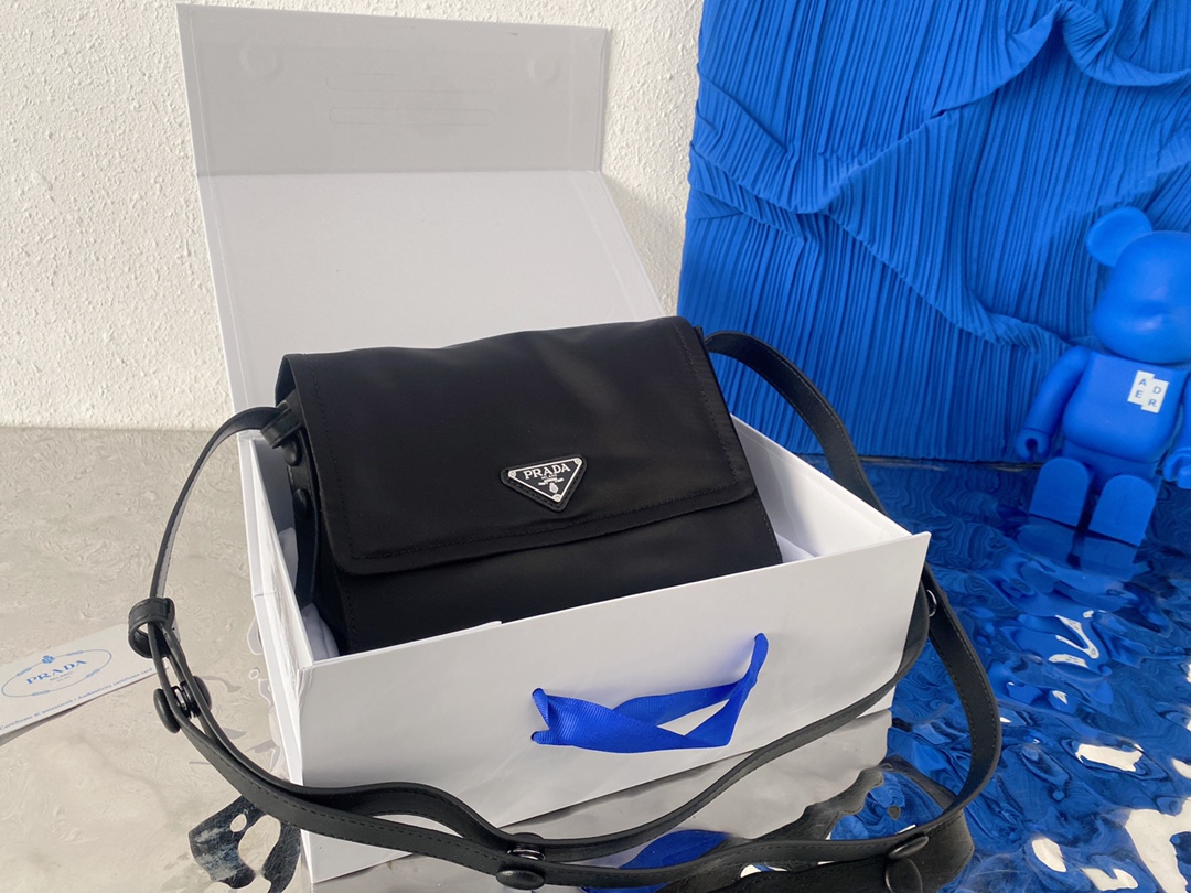 J5  普拉达 Prada  Re-Nylon 限定 invite联名系列 尼龙布翻盖邮差包 男女通用斜挎包 采用精湛镶嵌细工，经典百搭 实物拍摄 原厂原版面料 配送小票防尘袋 折叠礼盒 23 x 18 cm。