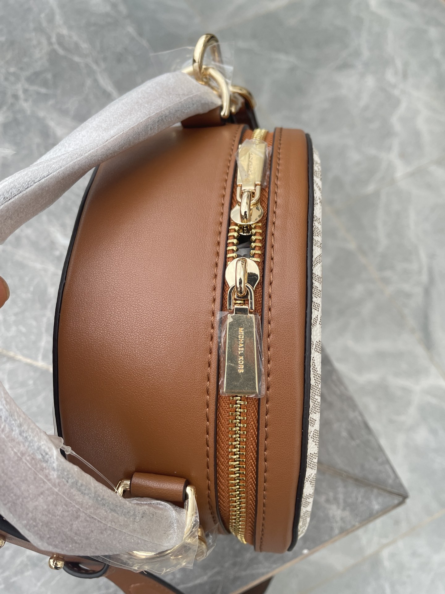 Michael Kors MK、新款Delaney 斜挎包采用 别致的圆饼造型 专为配合繁忙日程而设计 斜挎包以光滑皮革打造