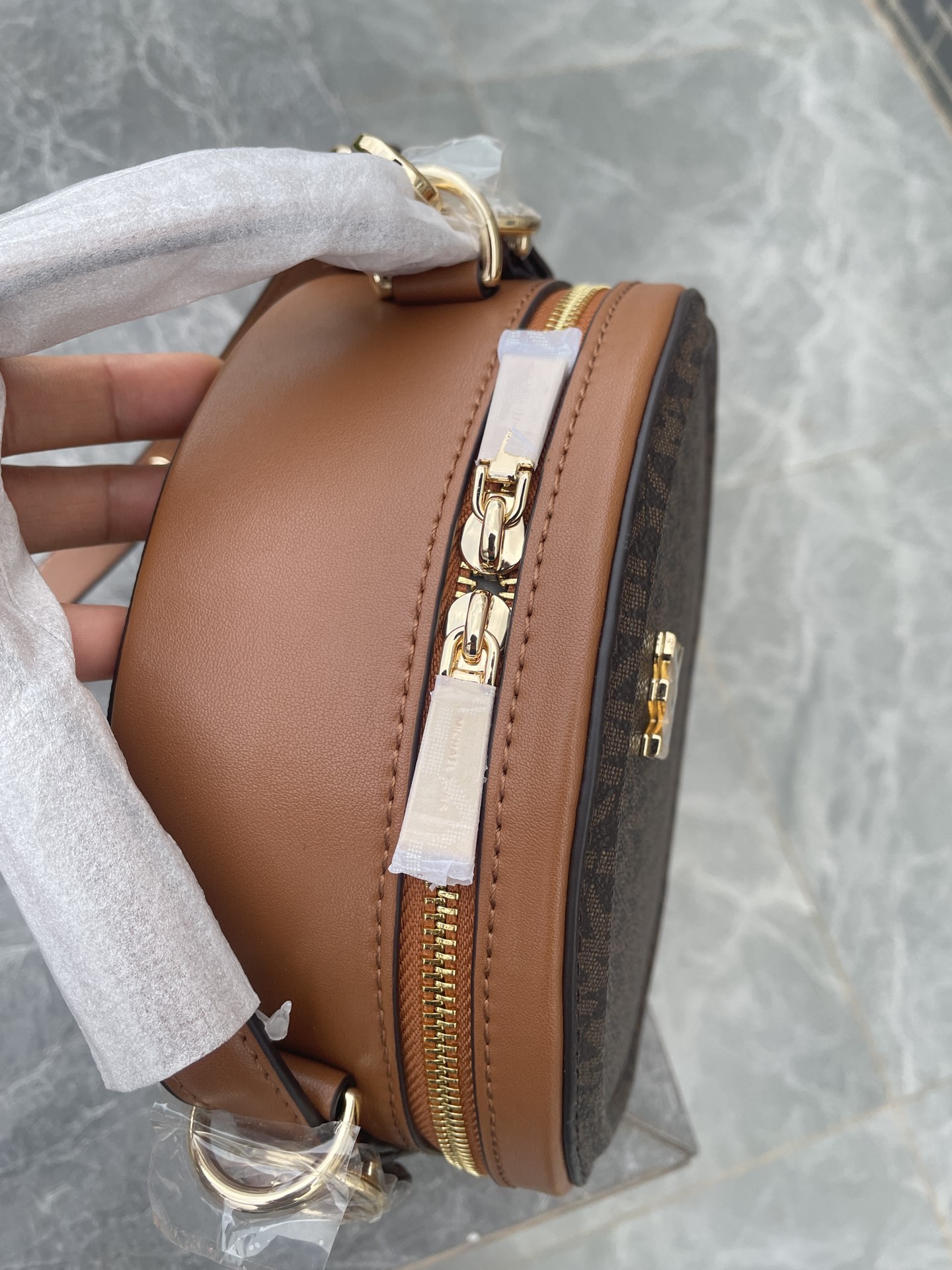Michael Kors MK、新款Delaney 斜挎包采用 别致的圆饼造型 专为配合繁忙日程而设计 斜挎包以光滑皮革打造