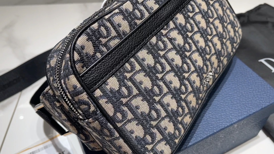 L5  Dior 迪奥  这款 Dior Lingot 22 手袋是本季新品，别具一格的实用设计，彰显 Dior 的现代风范。结构层次分明，经典帆布搭配对比鲜明的缉面线，正面饰以“DIOR”标志提升格调。拉链隔层搭配半开式外兜，可收纳各种日常用品。搭配可调节、可拆卸的肩带，带有钢扣，可肩背或斜挎。 黑色粒面牛皮革搭配对比鲜明的缉面线 正面金属覆层黄铜“DIOR”标志 内侧饰以“DIOR”标志 双向拉链开合搭配磁性翻盖 可调节、可拆卸的尼龙“CHRISTIAN DIOR”标志提花肩带 铝扣饰以“Christian Dior”标志和“CD”首字母