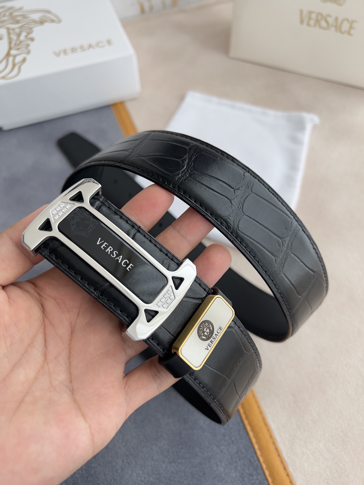 I5  VERSACE.范思哲原单腰带·皮带 型号：挂扣,经典人头亚克力纯钢材质挂扣,镶钻扣,图片实物拍摄 材料：百分百头层牛皮,保证真皮.24k纯钢扣双面可用专柜同等质量, 双面头层牛皮经典人头鳄鱼纹黑黑色平纹底,经典人头亚克力贴片扣,镶钻扣,银扣,送人自用首选 包装请认准如图专柜包装,赠送打孔器,原版电子发票,宽度3.8mm