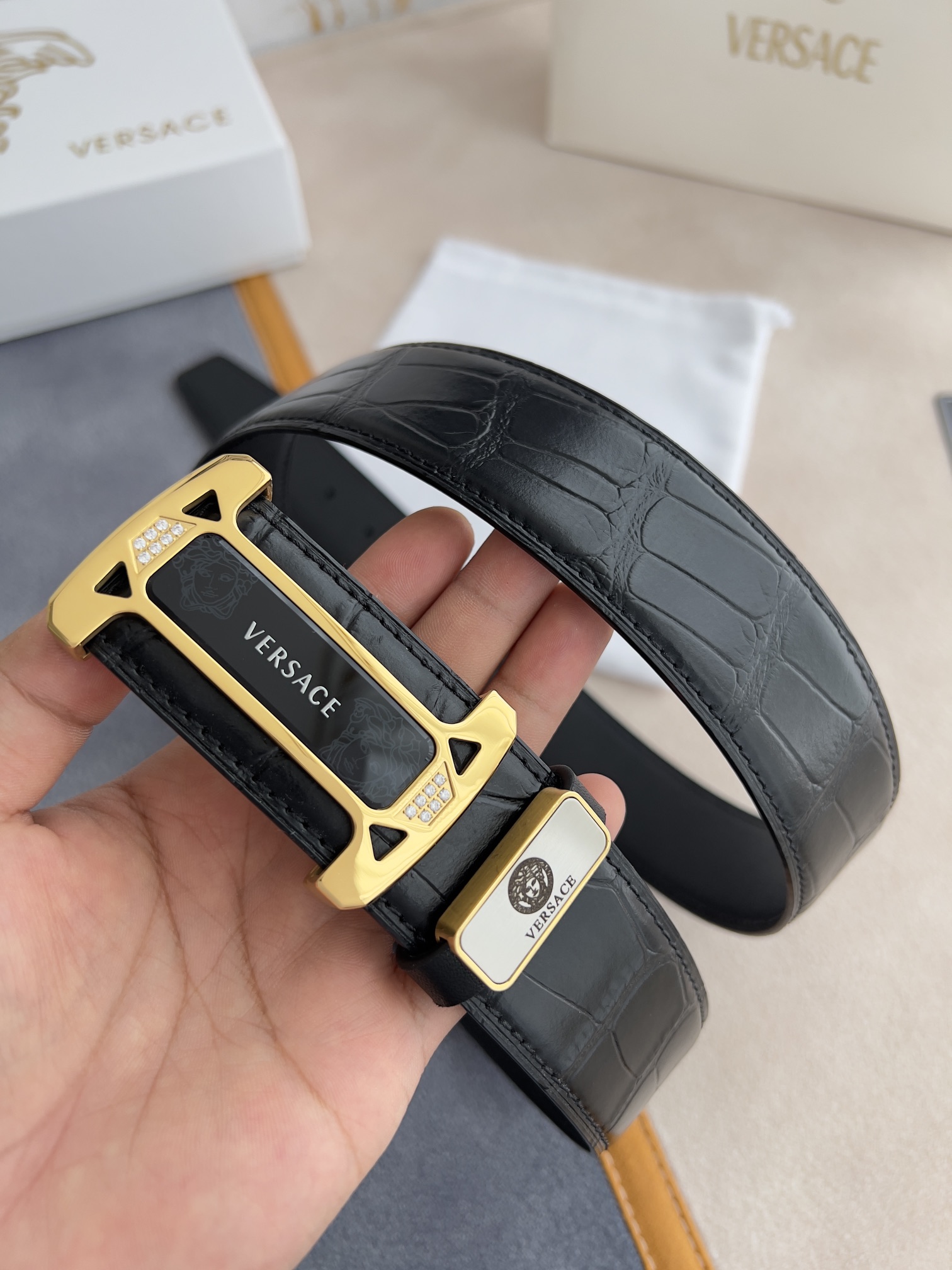 I5  VERSACE.范思哲原单腰带·皮带 型号：挂扣,经典人头亚克力纯钢材质挂扣,镶钻扣,图片实物拍摄 材料：百分百头层牛皮,保证真皮.24k纯钢扣双面可用专柜同等质量, 双面头层牛皮经典人头鳄鱼纹黑黑色平纹底,经典人头亚克力贴片扣,镶钻扣,送人自用首选 包装请认准如图专柜包装,赠送打孔器,原版电子发票,宽度3.8mm