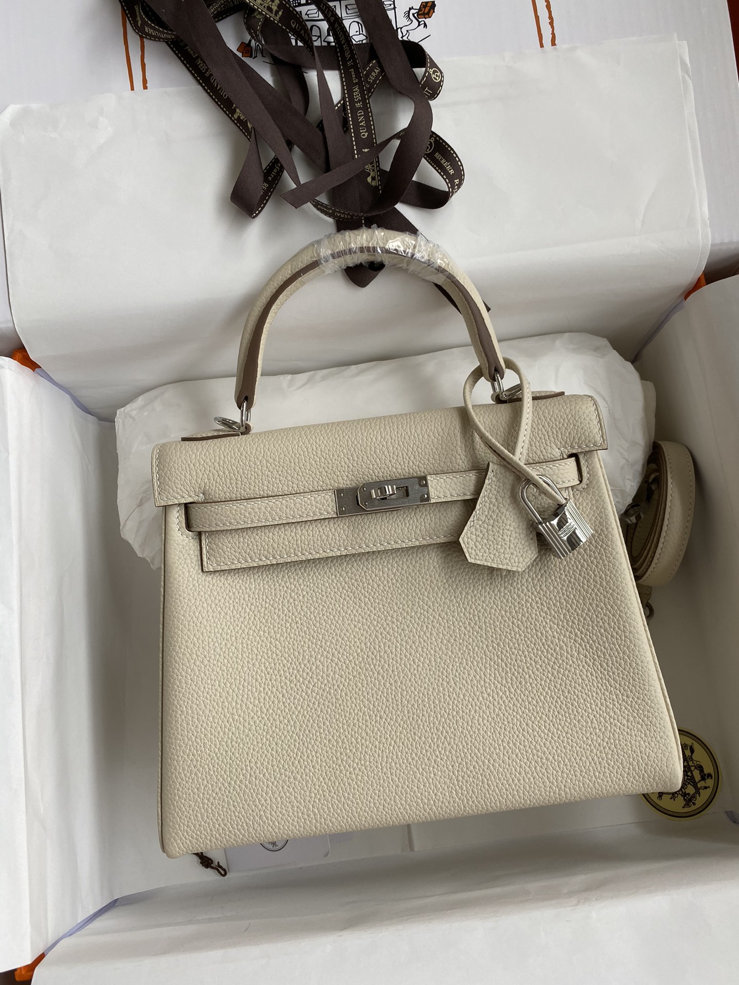 Kelly 25cm piel Togo importada, blanco batido, hebilla dorada y plateada