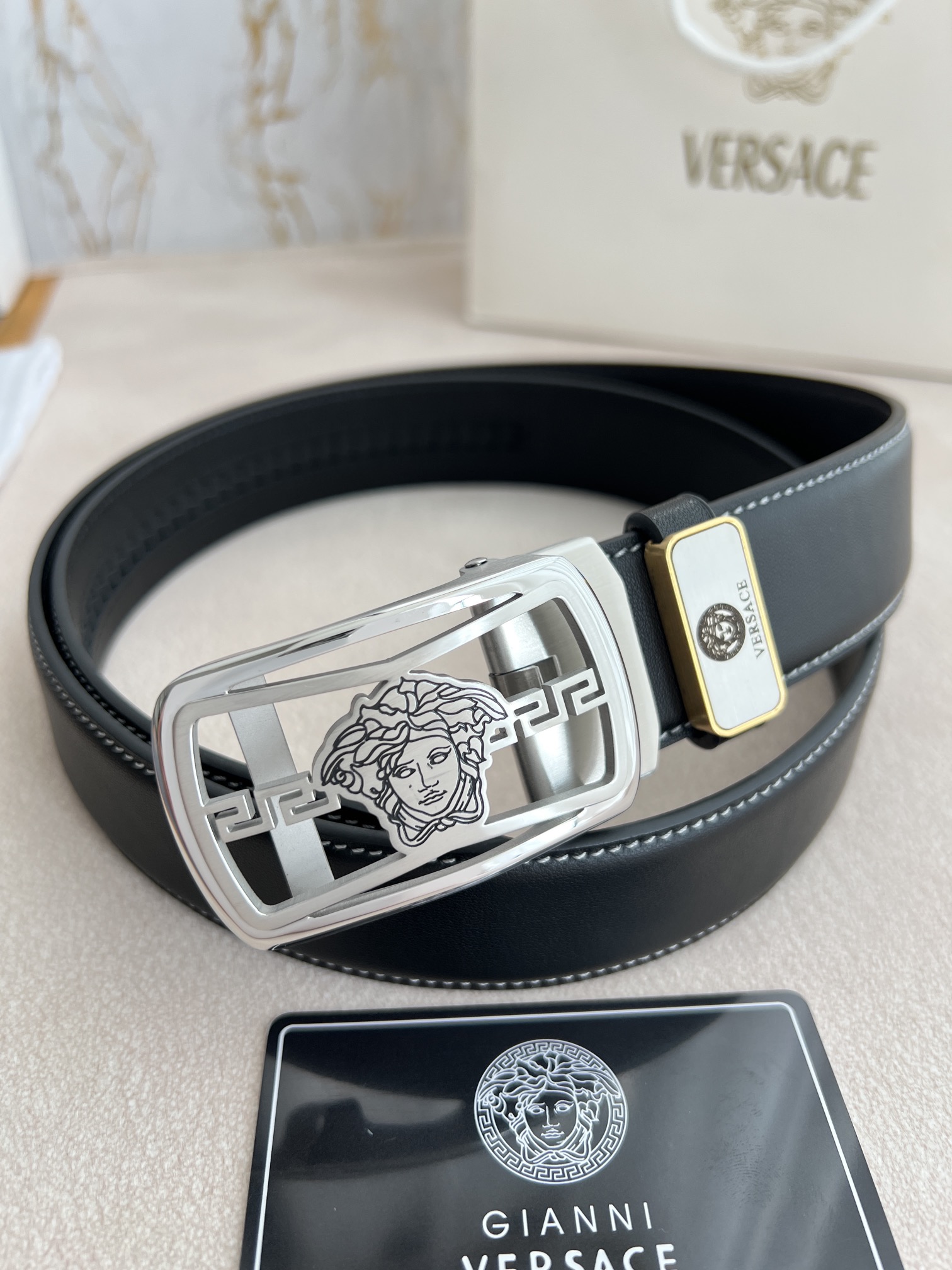 I5  Versace 范思哲 VERSACE.皮带腰带自动皮带p 型号：自动带身,纯钢材质经典人头自动扣,图片实物拍摄 腰带：百分百头层牛皮,自动带身,保证真皮.24k纯钢扣永不掉色专柜同等质量,经典头层牛皮平纹白线头层牛皮平纹底,银扣,镂空人头纯钢材质扣头,可自由裁剪,送人自用首选 包装请认准如图专柜包装,赠送拆卸工具,原版电子票,宽度3.5cm