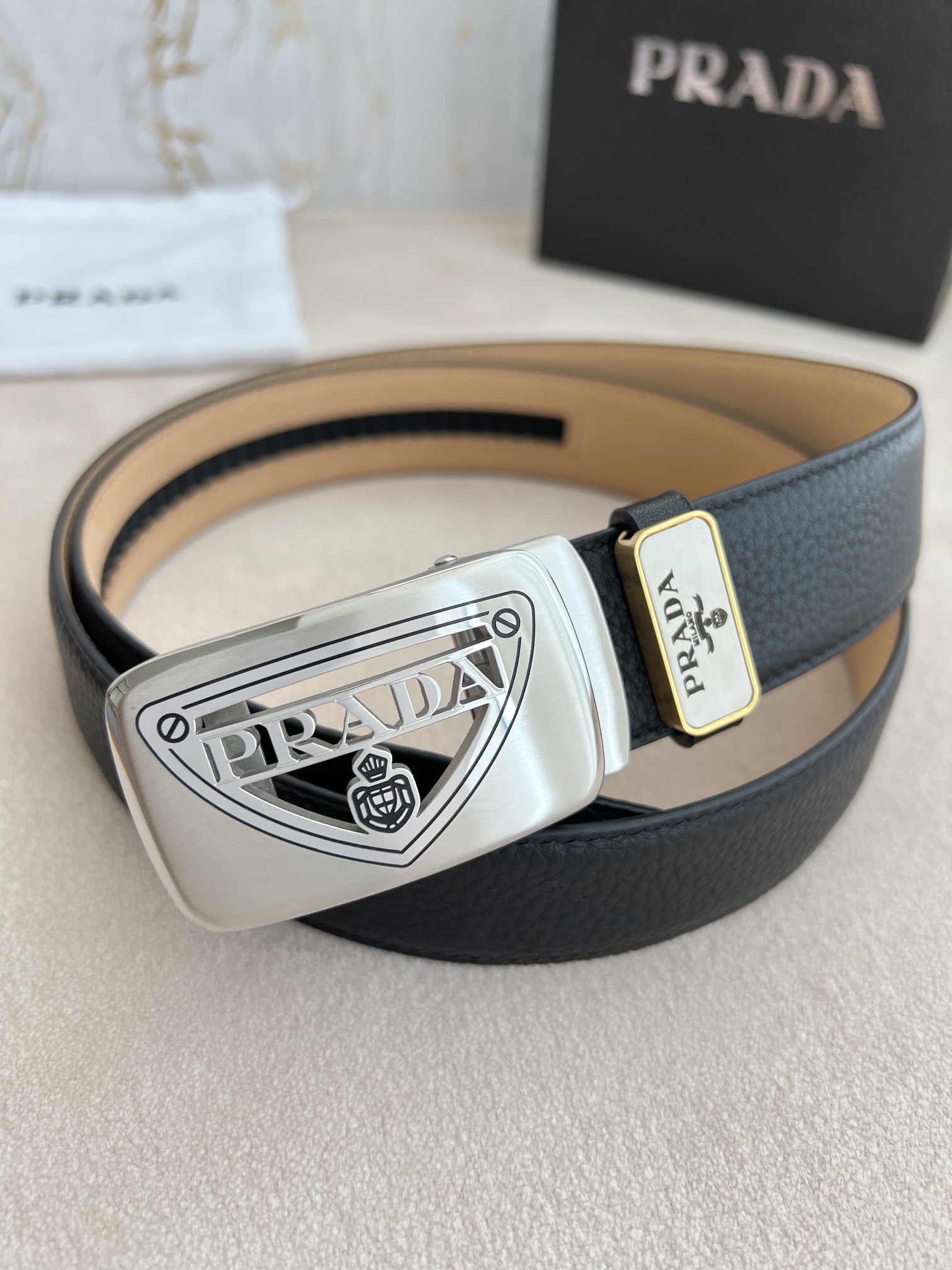 I5  Prada 普拉达  腰带·皮带自动带 型号：自动带,经典镂空纯钢材质自动扣,图片实物拍摄 材料：百分百头层牛皮,保证真皮.24k纯钢扣专柜同等质量, 双面头层牛皮荔枝纹头层树膏磨砂皮底,银扣,镂空纯钢材质自动扣,可自由裁剪,送人自用首选 包装请认准如图专柜包装,赠送装配工具,原版电子发票,宽度3.5cm