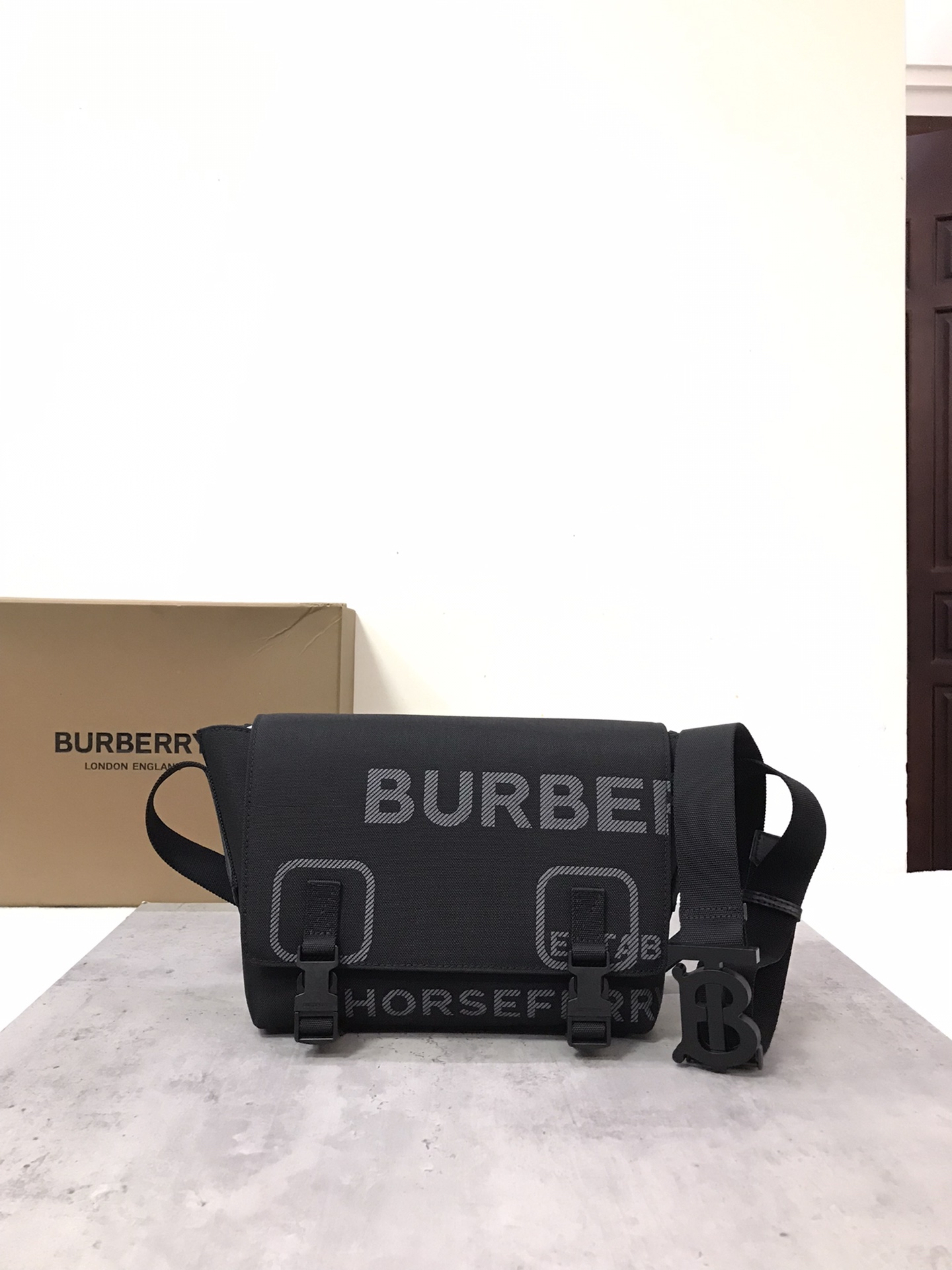 The original B family small Horseferry nylon messenger bag is made of nylon canvas. Details include the Horseferry print and the brand's signature hook closure. The casual style design is equipped with zipper pockets, making it easy to carry small items. It comes with adjustable straps for a relaxed backpacking experience. 20cm x 8cm x 26cm Outer: 100% cotton. Trim: 100% leather. Lining: 100% polyamide. Removable and adjustable shoulder strap. 1 zipped outer pocket; 1 zipped inner pocket. Top flap with hook clip closure.