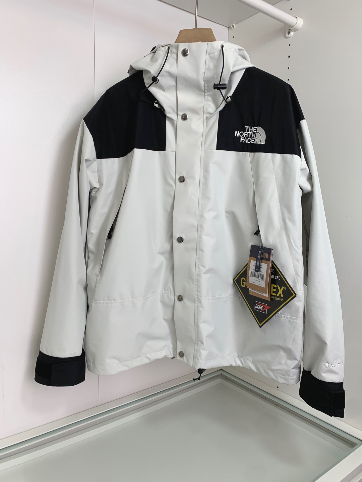 男士送礼精品 TNF 1990 Mountain Gore-Tex GTX冲锋衣 男女同款 TNF品牌1966年创立至今，其经典ICON产品如同一部部老电影，让人回味无穷。此次万众期待的mountain jacket 在1990年的原版基础上做了全面的升级 夹克面料选用防水材质 GORE-TEX2L配有塔夫绸和拉绒经编衬里 达到透气度与保暖度的高度结合 附加，可调节，腋下隐藏性拉链设计可透气调节。双中央正面防风罩采用按扣开合，VISLON中央正面拉链 反向进入高山口袋 可调节Velcro袖口标签 三个内袋 可调节下摆 兼容Zip-in 在胸部和背部的轭上绣上了NF徽标 前中VISLON拉链带以按扣和闭合的双层防风片 为户外活动提供全天候防风支持 配色方面承袭经典 以黑 白 为主 加持墨绿色 军绿色 抹茶绿 高辨度主色忠于原版撞色设计 尽显复古潮流 这次产品还有2方面的提升：1、防水为国际ISO标准90（ISO4）级别达到荷叶水珠滚动效果2、面料：高透层压织物Gore-tex仿水透气薄膜，手感更佳舒适。1990# 黑色 白色 墨绿色 军绿色 抹茶绿 S-XL， S码肩宽58胸围124衣长69袖长61； M码肩宽59胸围128衣长70袖长62； L码肩宽60胸围132衣长71袖长63； XL码肩宽61胸围136衣长72袖长64；