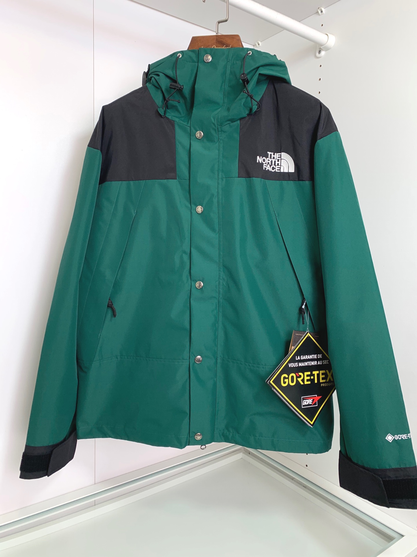男士送礼精品 TNF 1990 Mountain Gore-Tex GTX冲锋衣 男女同款 TNF品牌1966年创立至今，其经典ICON产品如同一部部老电影，让人回味无穷。此次万众期待的mountain jacket 在1990年的原版基础上做了全面的升级 夹克面料选用防水材质 GORE-TEX2L配有塔夫绸和拉绒经编衬里 达到透气度与保暖度的高度结合 附加，可调节，腋下隐藏性拉链设计可透气调节。双中央正面防风罩采用按扣开合，VISLON中央正面拉链 反向进入高山口袋 可调节Velcro袖口标签 三个内袋 可调节下摆 兼容Zip-in 在胸部和背部的轭上绣上了NF徽标 前中VISLON拉链带以按扣和闭合的双层防风片 为户外活动提供全天候防风支持 配色方面承袭经典 以黑 白 为主 加持墨绿色 军绿色 抹茶绿 高辨度主色忠于原版撞色设计 尽显复古潮流 这次产品还有2方面的提升：1、防水为国际ISO标准90（ISO4）级别达到荷叶水珠滚动效果2、面料：高透层压织物Gore-tex仿水透气薄膜，手感更佳舒适。1990# 黑色 白色 墨绿色 军绿色 抹茶绿 S-XL， S码肩宽58胸围124衣长69袖长61； M码肩宽59胸围128衣长70袖长62； L码肩宽60胸围132衣长71袖长63； XL码肩宽61胸围136衣长72袖长64；