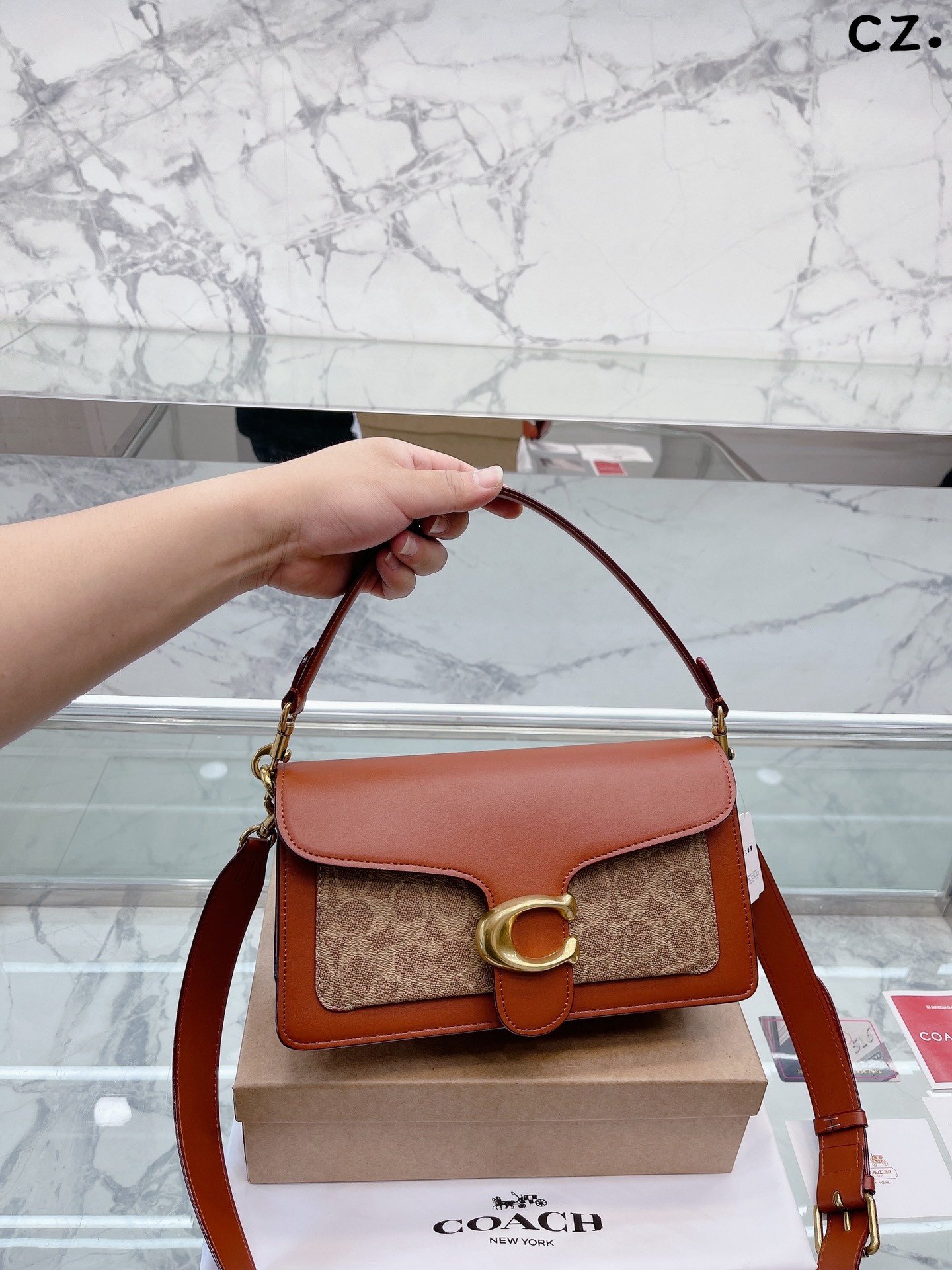 J5 Coach 家酒神包Tabby手提包单肩斜挎包。让小姐姐第一眼看到就会爱上它。被誉为平价版小酒神包的 Coach 蔻驰 Tabby，复古又百搭，很受欢迎啊。五金扣厚实，整体精致小巧，还特别能装。每个包配一长一短两天可卸肩带，内部结构分层合理，中间一个带拉链的隔层小袋，把包分成三格，简直完美尺寸：25*15*7.5cm。这个尺寸觉得刚刚好合适，手提单肩斜挎都没有问题的礼盒包装