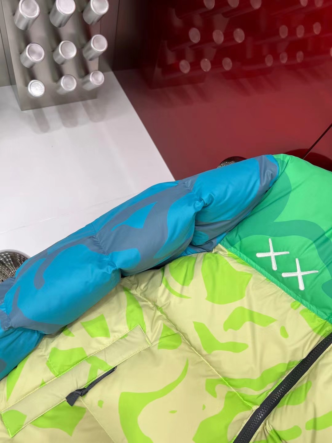 North Face x KAWS 1996 Nuptse collaboration in green and gray. Sizes XS-XXL. Bold design with vibrant colors and KAWS graphics.-Big cat