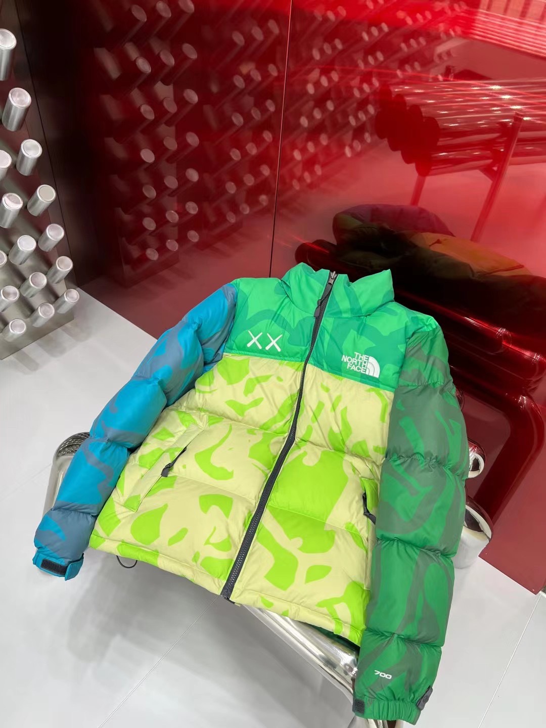North Face x KAWS 1996 Nuptse collaboration in green and gray. Sizes XS-XXL. Bold design with vibrant colors and KAWS graphics.-Big cat
