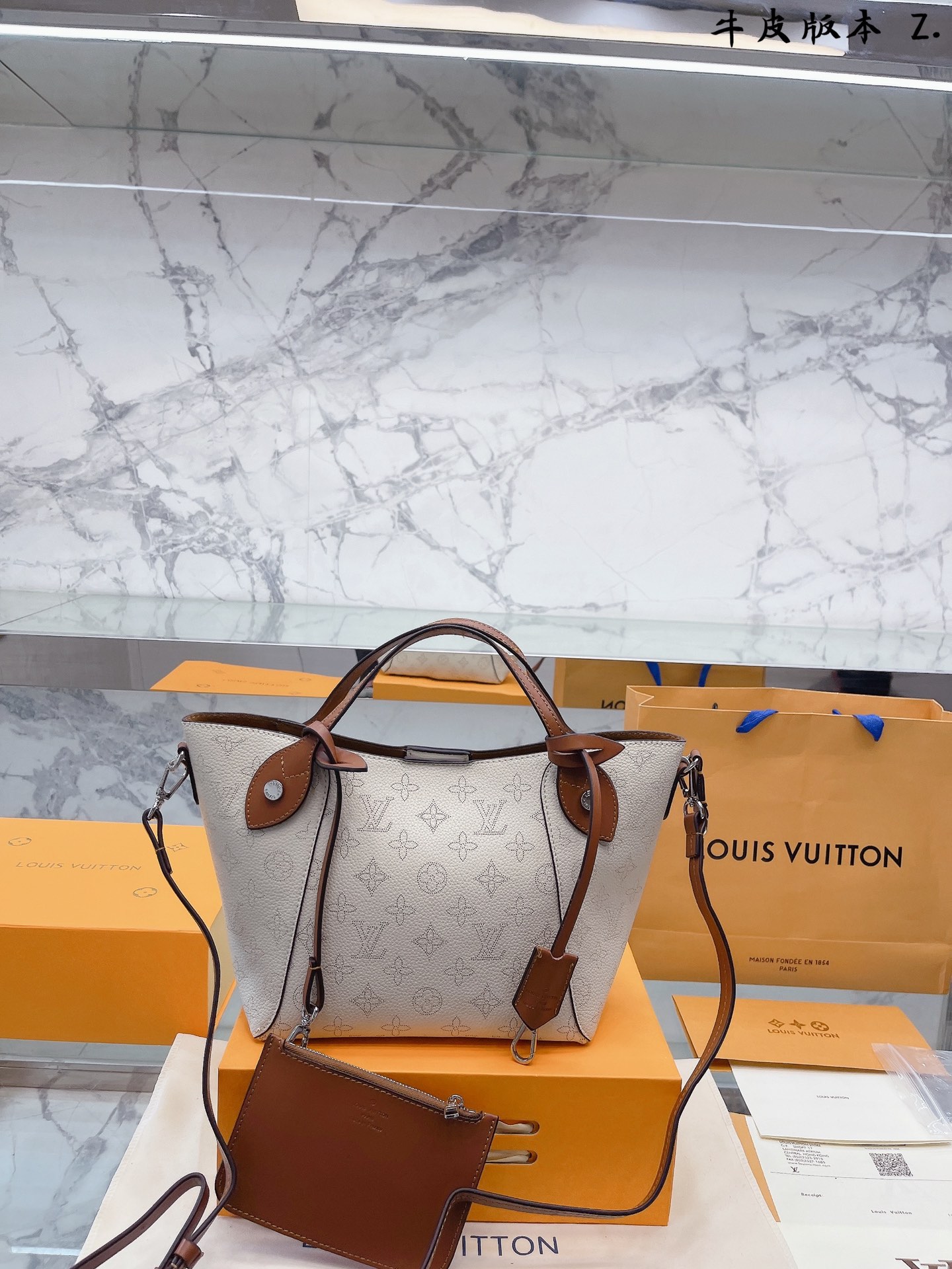 K0 牛皮版本 “ Louis Vuitton 路易威登 LV  Mahina” 小号手袋M54353采用双重设计的Hina手袋：包身正中配有弹簧扣，可折叠，可伸展，在Tote手袋与摩登水桶包之间自如切换。由小牛皮裁制而成并采用镂花装饰，轻质而舒适，日常背携的理想之选。小号尺寸，配有一条可拆卸包带，方便斜挎。20 21cm – Mahina镂花小牛皮- 小牛皮饰边- 超细纤维内衬- 银色金属配饰- 2个手柄，可手提，可手挎- 可脱卸、不可调节包带，方便肩背或斜挎- 内配可脱卸拉链袋，以细皮绳固定- 磁吸扣合- 外侧配有弹簧扣- 钥匙罩- 4个保护底钉