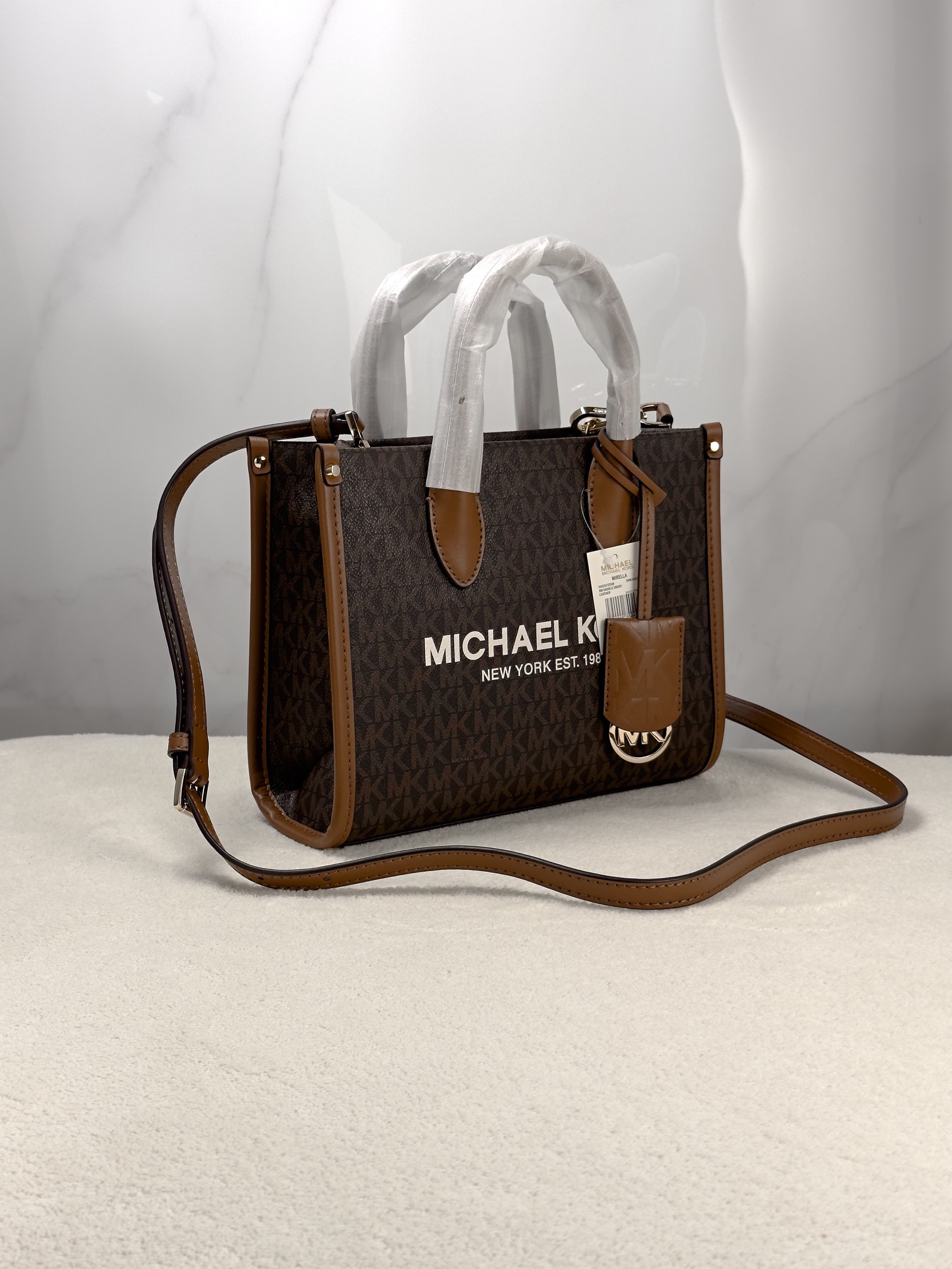 Michael Kors 印花打造包身，上缀 Michael Kors 字母印花装饰，皮革