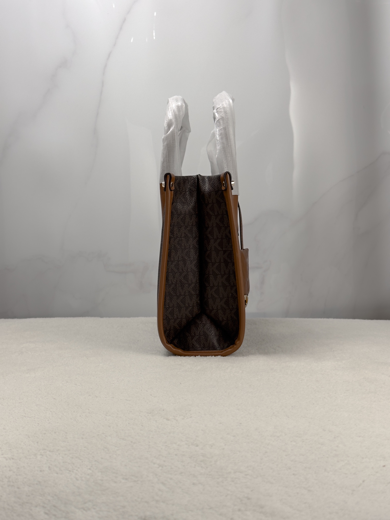 Michael Kors 印花打造包身，上缀 Michael Kors 字母印花装饰，皮革