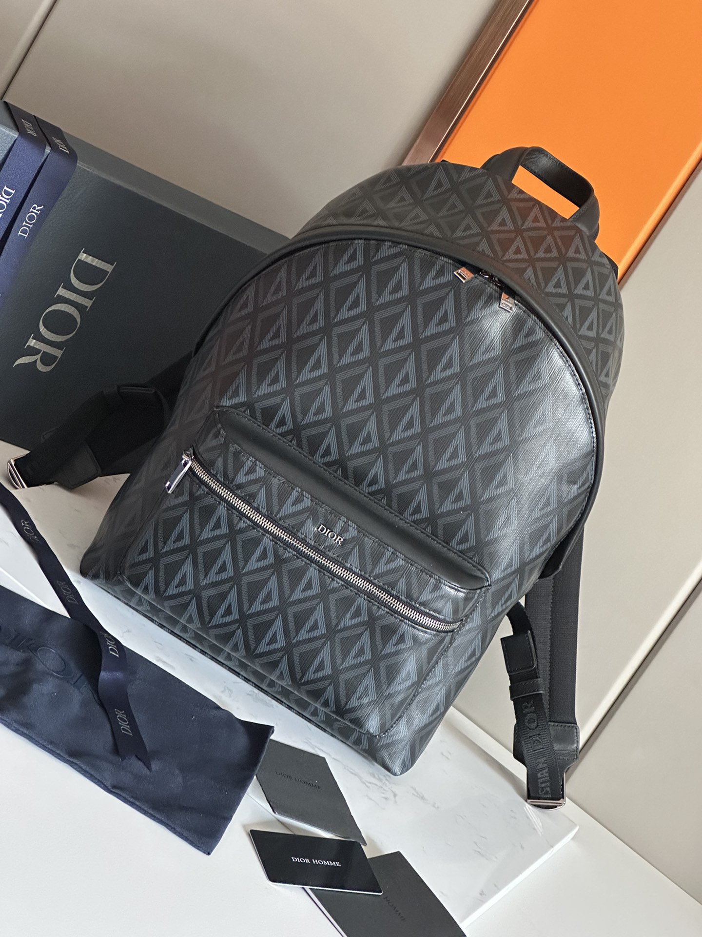 NO:395006,48 This Rider backpack is simple in outline, and the classic Academy style is full of vitality. It is carefully crafted from the black CD Diamond pattern canvas, drawn inspiration from the Dior archives, embellished with smooth cowhide leather, and the front is decorated with the 'DIOR' logo to enhance the style. Continuing the classic design, paired with exquisite details such as bidirectional zipper closures, large zipper pockets on the front and adjustable padded shoulder straps, is ideal for everyday design. Black Canvas CD Diamond pattern designed by Marc Bohan in 1974 reinterprets the 'CD' first letter in a three-dimensional line rhombus pattern, presented in canvas fabric black smooth cowhide leather metal clad brass 'DIOR' logo  Interior embossed with DIOR embossed logo Two-way zipper closure Adjustable padded nylon shoulder strap Top leather handle Reinforced with quilted mesh fabric Front zippered pocket Number: 93328 Black Canvas Gray Canvas Dimensions 30 x 42 x 15 cm Storage 15-inch laptops, files and tablets, Dior, dior, backpacks, cowhide1986090948 这款 Rider 双肩背包轮廓简约,经典的学院款式洋溢着活力.采用黑色 CD Diamond 图案帆布精心制作,从 Dior 档案汲取灵感,点缀以光滑牛皮革,正面饰以“DIOR”标志提升格调.延续经典设计,搭配双向拉链开合、正面大号拉链口袋以及可调节的加垫肩带等精美细节,是日常造型的理想之选. 黑色帆布 CD Diamond 图案 马克·博昂 (Marc Bohan) 于 1974 年设计的 CD Diamond 图案以立体线条菱形图案重新诠释“CD”首字母,呈现于帆布面料 黑色光滑牛皮革 正面金属覆层黄铜“DIOR”标志 内部饰以“DIOR”压花标志 双向拉链开合 可调节的加垫尼龙肩带 顶部皮革手柄 背部采用绗缝网眼织物加固 正面拉链口袋 编号: 93328黑帆布灰帆布 尺寸30 x 42 x 15 厘米 可收纳 15 英寸笔记本电脑、文件和平板电脑,迪奥,dior,dior,backpacks,cowhide,Bag