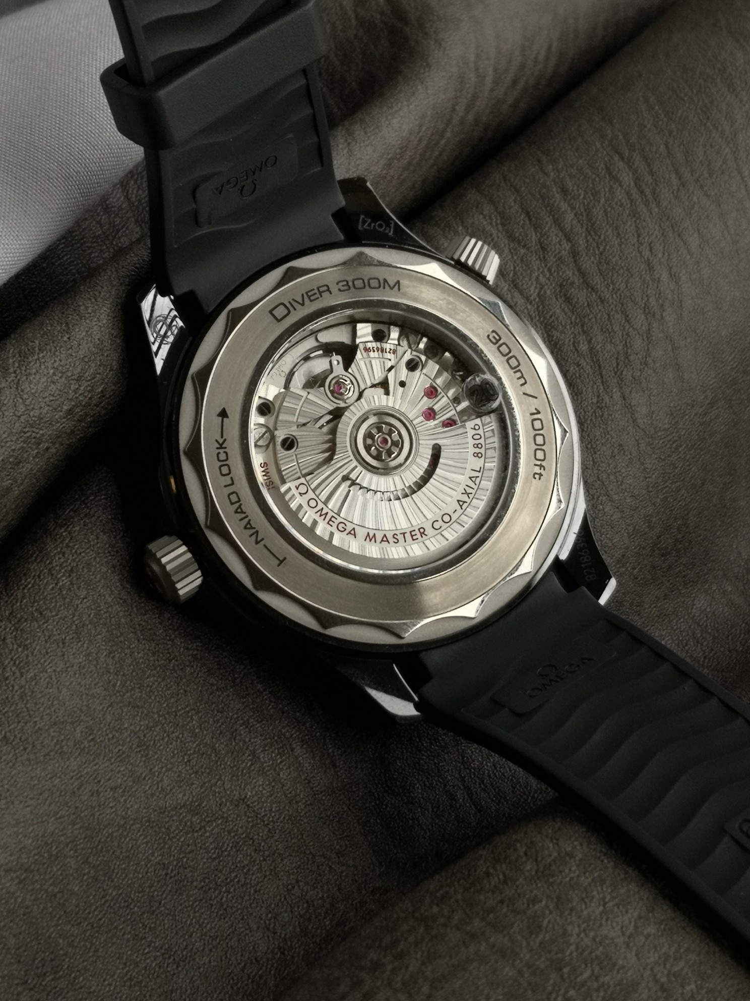 Omega 黑色陶瓷表壳搭配天然橡胶表带 以抛光黑色陶瓷制成 饰以激光携刻波纹图案 钛金属镂空指针和浮雕小时刻度采用PVD镀层
