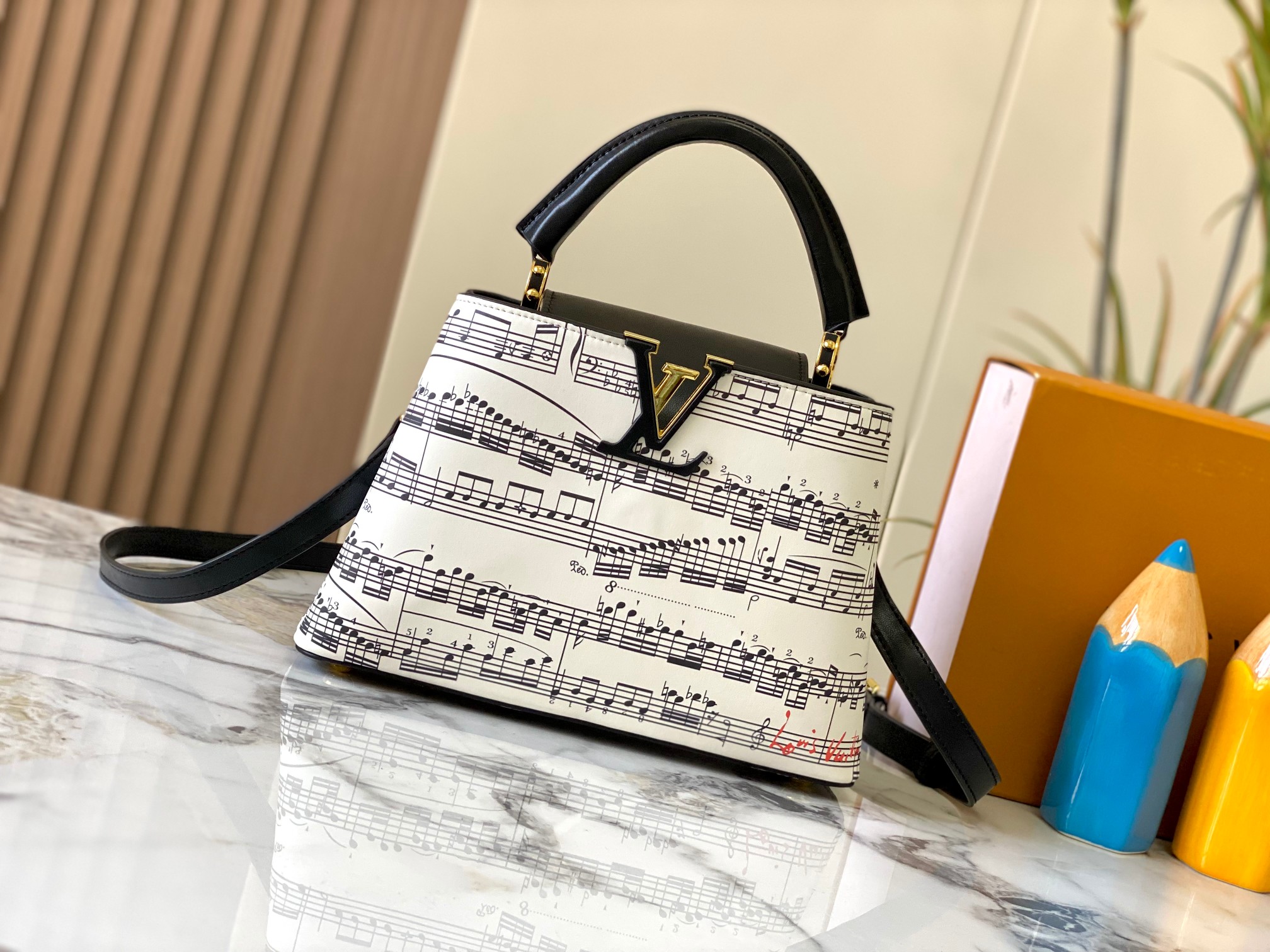 p370  广州货M20194白色配黑音符🎵 本款Capucines 中号手袋 法国进口小牛皮,闪亮的金属饰件,特有的Capucines搭盖既可收入包内展示字母标识,又可外翻 呈现Monogram Flower图案 
size:27 x 18 x 9 厘米