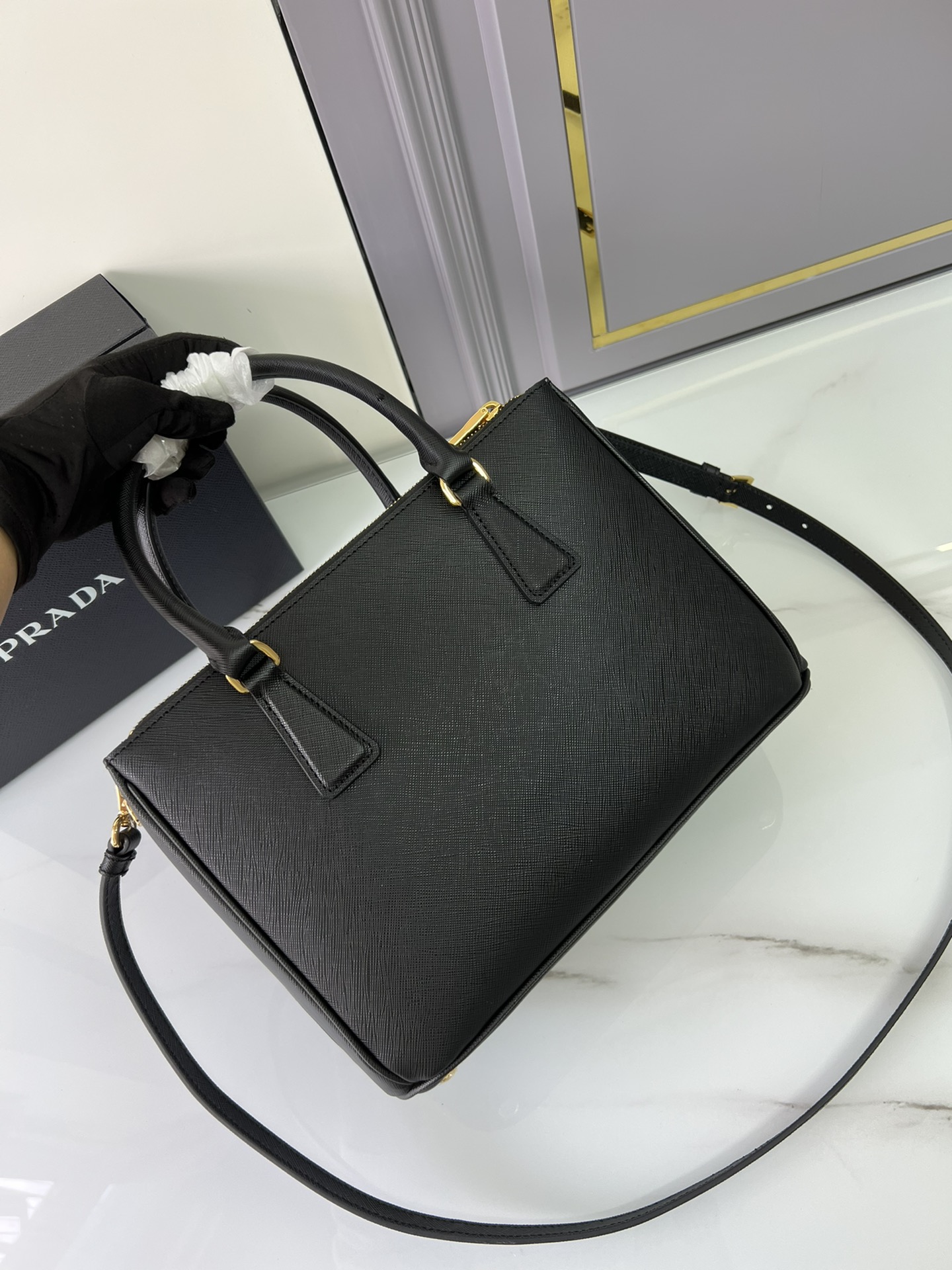 Small Prada killer bag, double handles in Saffiano leather. Detachable and adjustable leather shoulder strap. Gold-plated hardware. Triangular le
