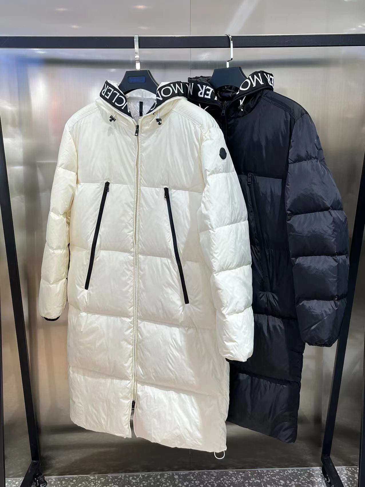Moncler long jacket with 80s inspiration. Waterproof, insulated, embroidered logo. Hooded nylon quilted design. Colors: black, white. Sizes available.-Big cat