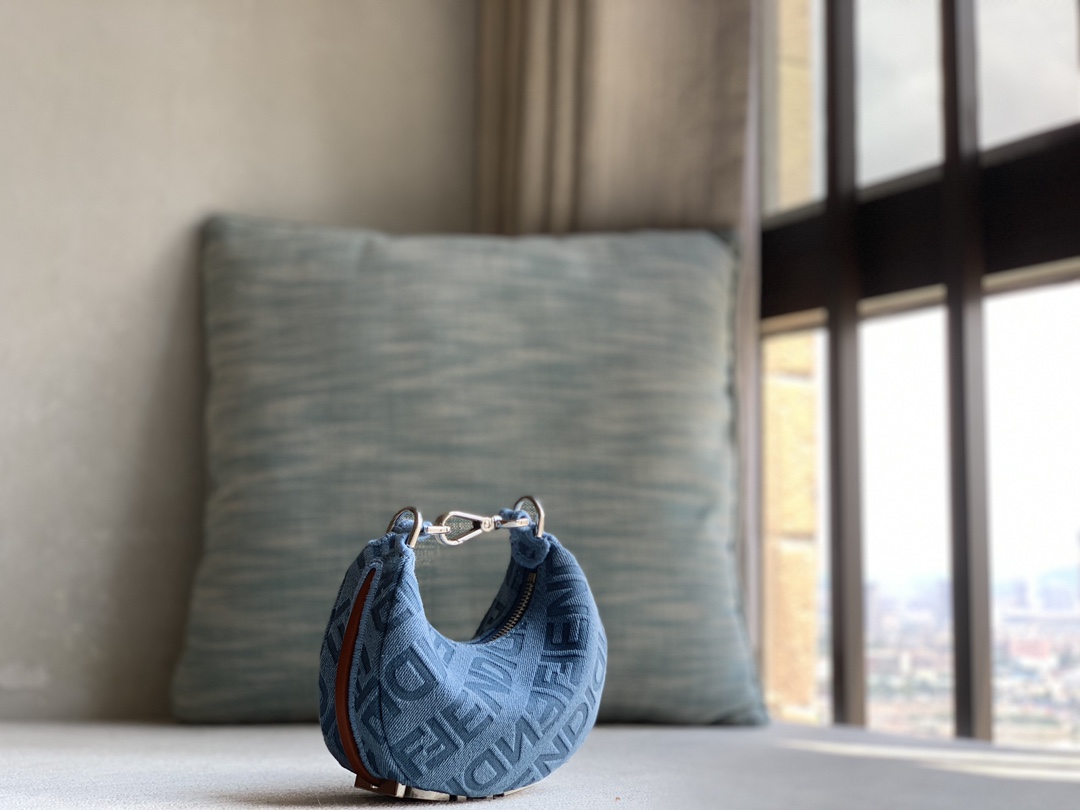 Fendi Mini Nano Crescent bag in light blue denim with FENDI Mirror pattern all over and brown leather details. When the handbag is carried under