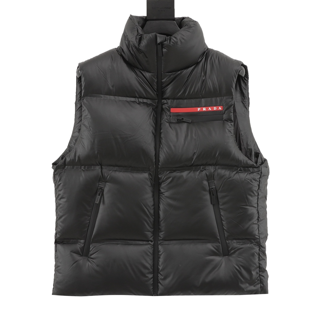 款号y603 Prada/普拉达 轻薄羽绒马甲 Prada爆款马甲羽绒服难得的好看 此款廓形丰满的羽绒外套采用 Prada Linea rossa独特的 双层轻质粘合尼龙面料打造 搭配连帽衣领、直裁衣袖和正面拉链拉合,与横向绗缝 元素和下摆弹力束绳共同塑造鲜明廓形 轻质粘合尼龙科技面料具有防风、耐磨、防水和透气等 高科技性能,是一款多功能科技面料 衬里采用精细密实的可再生微纤维面料打造,触感轻盈 柔软,鹅绒和 Graphene加衬有助于调节体温,别具功能 性 鹅绒材质赋予加衬填料更加轻盈的特色,提升服装的保 温性能.003