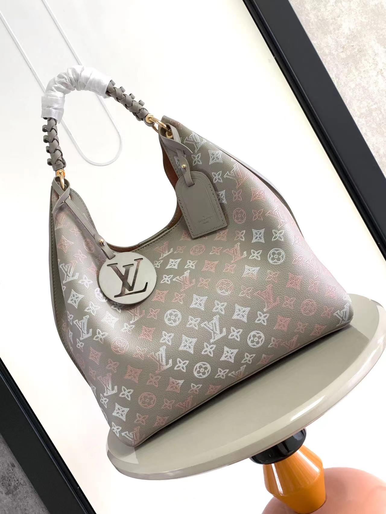 NO:551900,M23396m53188 This Carmel bag is made from Mahina perforated calfskin, its understated color scheme perfectly matches the light gold ring connecting the woven leather top handle to the bag. Lightweight and body-friendly, it has space for essentials and an internal zippered pocket for valuables. 35×40×17cm (LxHxW),,cowhide19860909M23396m53188 这款Carmel包由Mahina穿孔小牛皮制成,其低调的配色与连接编织皮革顶部提手与包的浅金色环完美搭配.重量轻,身体友好,它有空间的必需品和一个内部拉链口袋贵重物品. 35×40×17cm（长x高x宽）,,cowhide,Bag