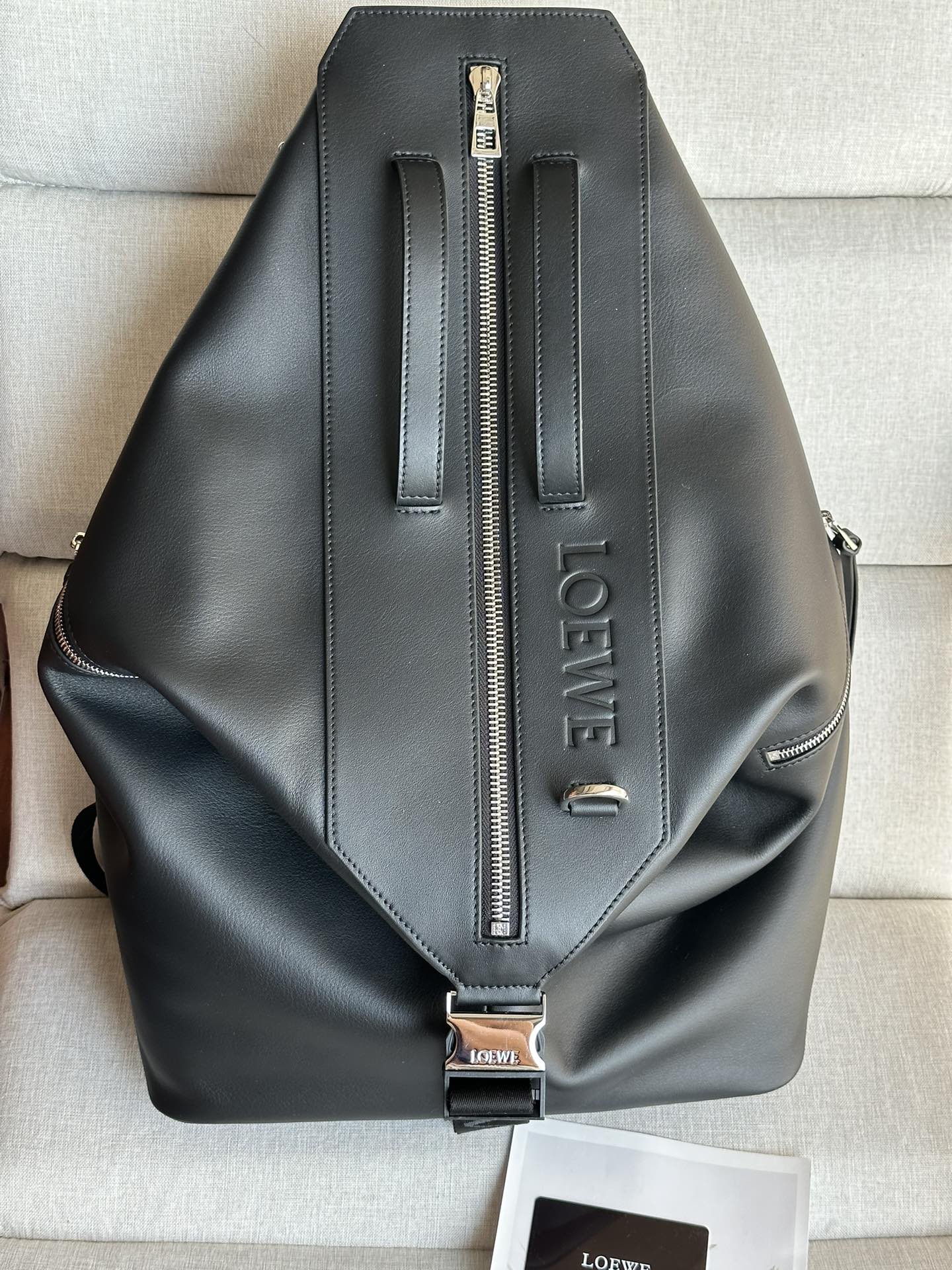 NO:617883,Premium Loewe model large school bag Classic cow leather convertible backpack Size 40-20-50cm Color: Black Multifunctional backpack with padded shoulder straps for comfort, mesh back and a metal buckle with branding, can be opened and converted into a double handle travel bag. The external flat zipper pocket has enough space to hold a tablet. This version is made of classic cow leather. Carry as a backpack, shoulder or top handle Adjustable shoulder straps Zip closure, cowhide zip puller Two zippered side pockets and one large zippered pocket Holds a 13-inch laptop Herringbone cotton canvas lining Embossed with D-rings LOEWE, Premium Loewe, loewe, loewe, travel bags, backpacks, cowhide19860909特级 Loewe型號大号书包  经典牛皮革变形背包 尺寸40-20-50cm 颜色: 黑色 多功能背包,配有舒适性高的衬垫肩带,网眼背部和一个饰有品牌标志的金属扣,可打开并转换为双提手旅行包.外部扁平拉链口袋有足够的空间可以容纳一台平板电脑.此版本采用经典牛皮革制成. 双肩背、肩背或顶部提手携带 可调节肩带 拉链开合,牛皮革拉链头 两个拉链侧袋和一个大拉链口袋 可容纳 13 英寸笔记本电脑 人字纹棉质帆布衬里 配有 D 形环的压纹 LOEWE,特级罗意威,loewe,loewe,travel bags,backpacks,cowhide,Bag