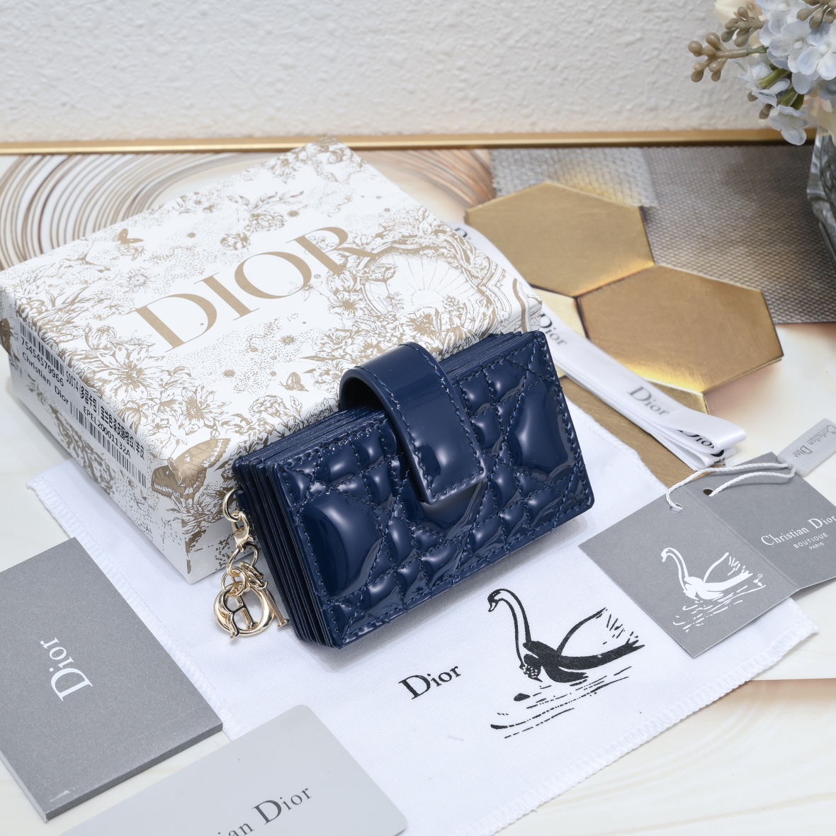 Dior 这款 Lady 5 格卡夹饰有 的藤格纹缉面线 采用外面亮漆皮+内裡羊皮精心制作