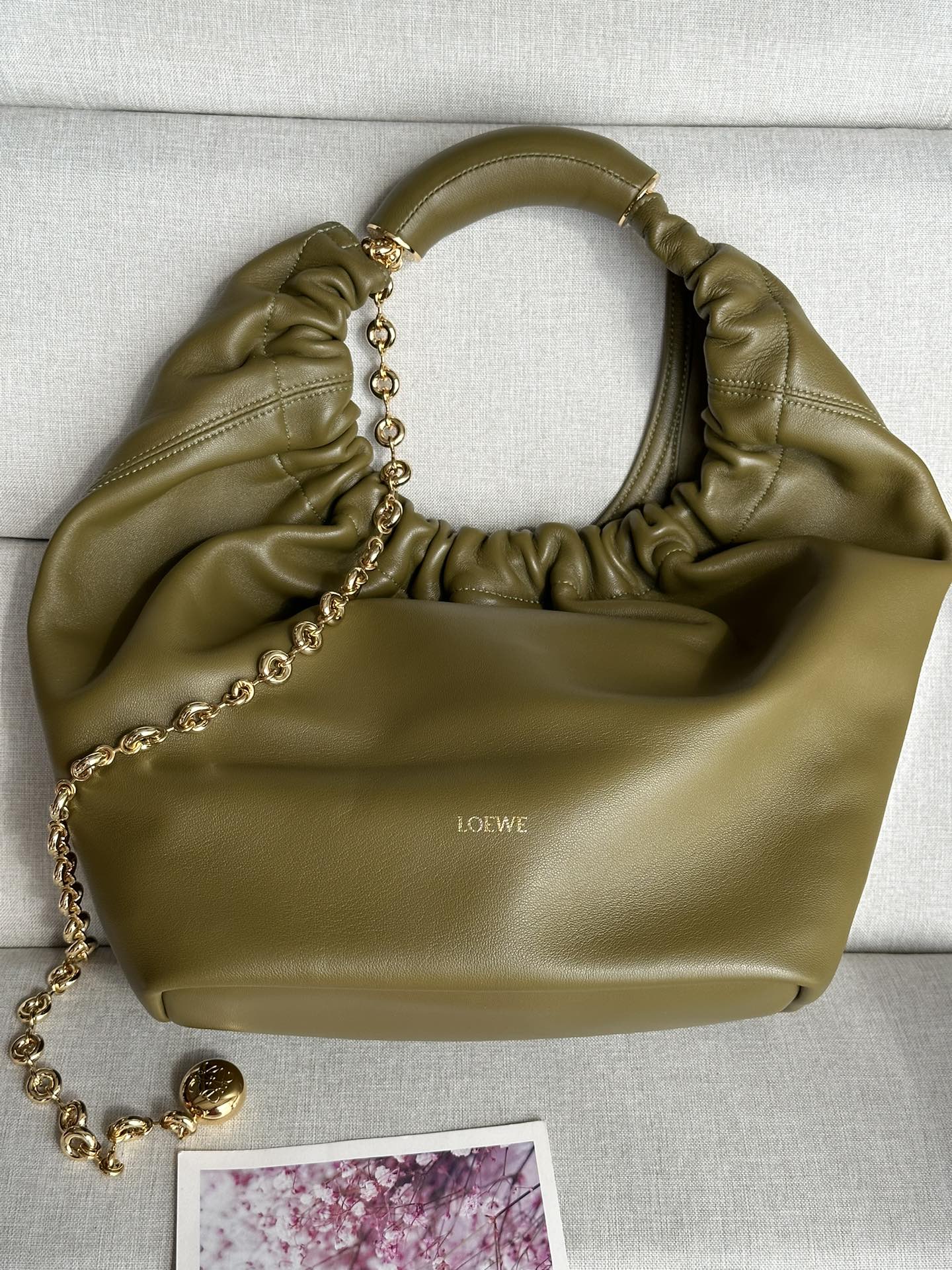 NO:175940,LOw Medium 3902 Olive Green 0. Napa Sheepskin Squeeze Handbag A new exquisite and soft handbag made of soft-touch Napa leather. This craft is a masterpiece of traditional craftsmanship, innovative research and unique design, with a surprisingly lightweight pleated body, adjustable donut chain and soft-touch handle. This medium version is made of Napa Sheepskin.* shoulder-mounted, cross-body or hand-held* adjustable chain straps, paired with Anagram carved pebbles, additional chains for further extensions* magnetic buckle closure* internal zipper pocket* unlined*lo*ewe gold or silver hot. size34*13.5*33CM, extra Loewe, sheepskin19860909LOw中号 3902 橄欖绿 0. 纳帕羊皮Squeeze手袋一款精致而柔美的全新手袋,采用触感柔软的纳帕皮革制成.这款顺手艺是传统工艺、创新研究和独特设计的杰作,具备令人惊讶的轻盈褶皱包身、可调节甜甜圈链条和触感柔软的提手.此中号版本采用纳帕羊皮革打造.*可肩背、斜挎或手提*可调节链条肩带,搭配Anagram携刻鹅卵石,附加额外链条,可进一步延长肩带*磁扣开合*内部拉链口袋*无衬里*lo*ewe烫金或烫银. size34*13.5*33CM,特级罗意威,loewe,sheepskin,Bag