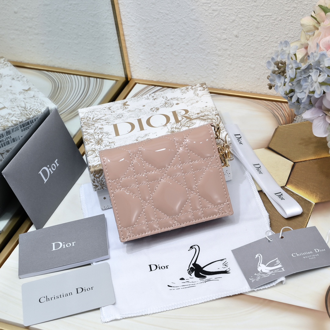 Dior 这款翻盖卡夹采用黑色漆皮牛皮革精心制作，彰显Lady r 系列 设计，搭配藤格纹缉面线和D.I.O.R.吊饰