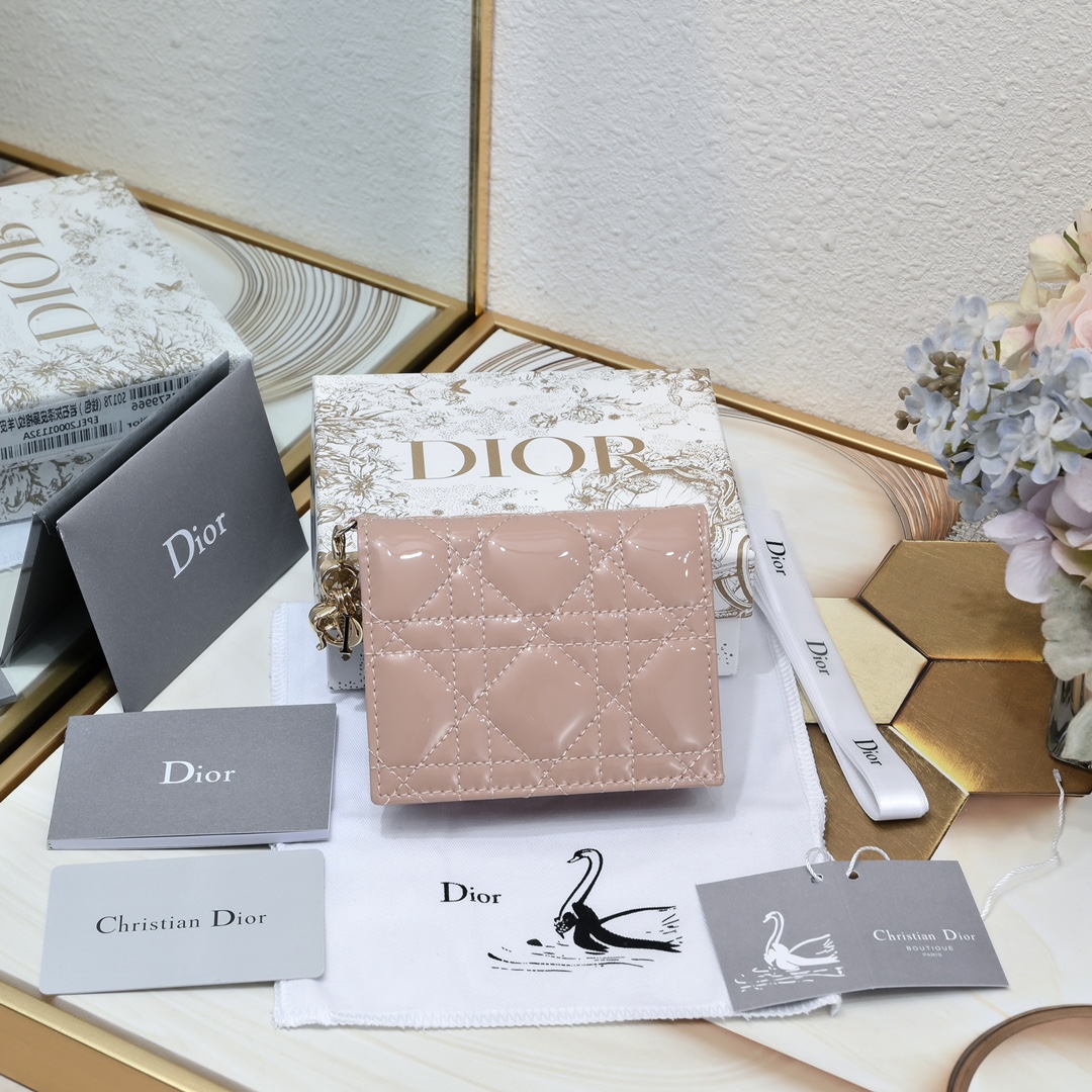 Dior 这款翻盖卡夹采用黑色漆皮牛皮革精心制作，彰显Lady r 系列 设计，搭配藤格纹缉面线和D.I.O.R.吊饰