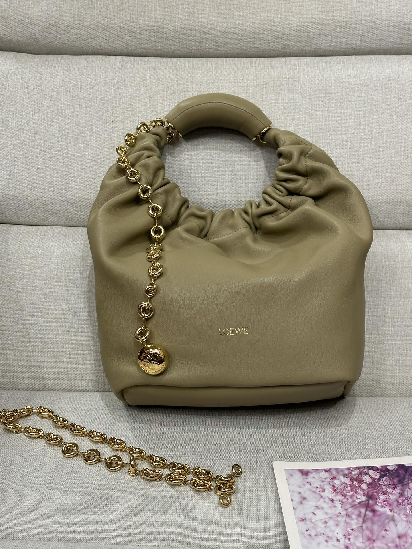 NO:175931,LOw Small Model 3901 Clay Green Napa Sheepskin Squeeze Handbag A new exquisite and soft handbag made of soft-touch Napa leather. This craft is a masterpiece of traditional craftsmanship, innovative research and unique design, with a surprisingly lightweight pleated body, adjustable donut chain and soft handle. This small version is made of Napa Sheepskin.* shoulder-mounted, cross-body or hand-held* adjustable chain straps, paired with Anagram carved pebbles, additional chains for further extensions* magnetic buckle closure* internal zipper pocket* unlined*lo*ewe gold or silver hot. size29*10.5*24CM All-steel hardware, special grade Loewe, sheepskin19860909LOw小号 型號3901 黏土绿 纳帕羊皮Squeeze手袋一款精致而柔美的全新手袋,采用触感柔软的纳帕皮革制成.这款顺手艺是传统工艺、创新研究和独特设计的杰作,具备令人惊讶的轻盈褶皱包身、可调节甜甜圈链条和触感柔软的提手.此小号版本采用纳帕羊皮革打造.*可肩背、斜挎或手提*可调节链条肩带,搭配Anagram携刻鹅卵石,附加额外链条,可进一步延长肩带*磁扣开合*内部拉链口袋*无衬里*lo*ewe烫金或烫银. size29*10.5*24CM 全钢五金,特级罗意威,loewe,sheepskin,Bag