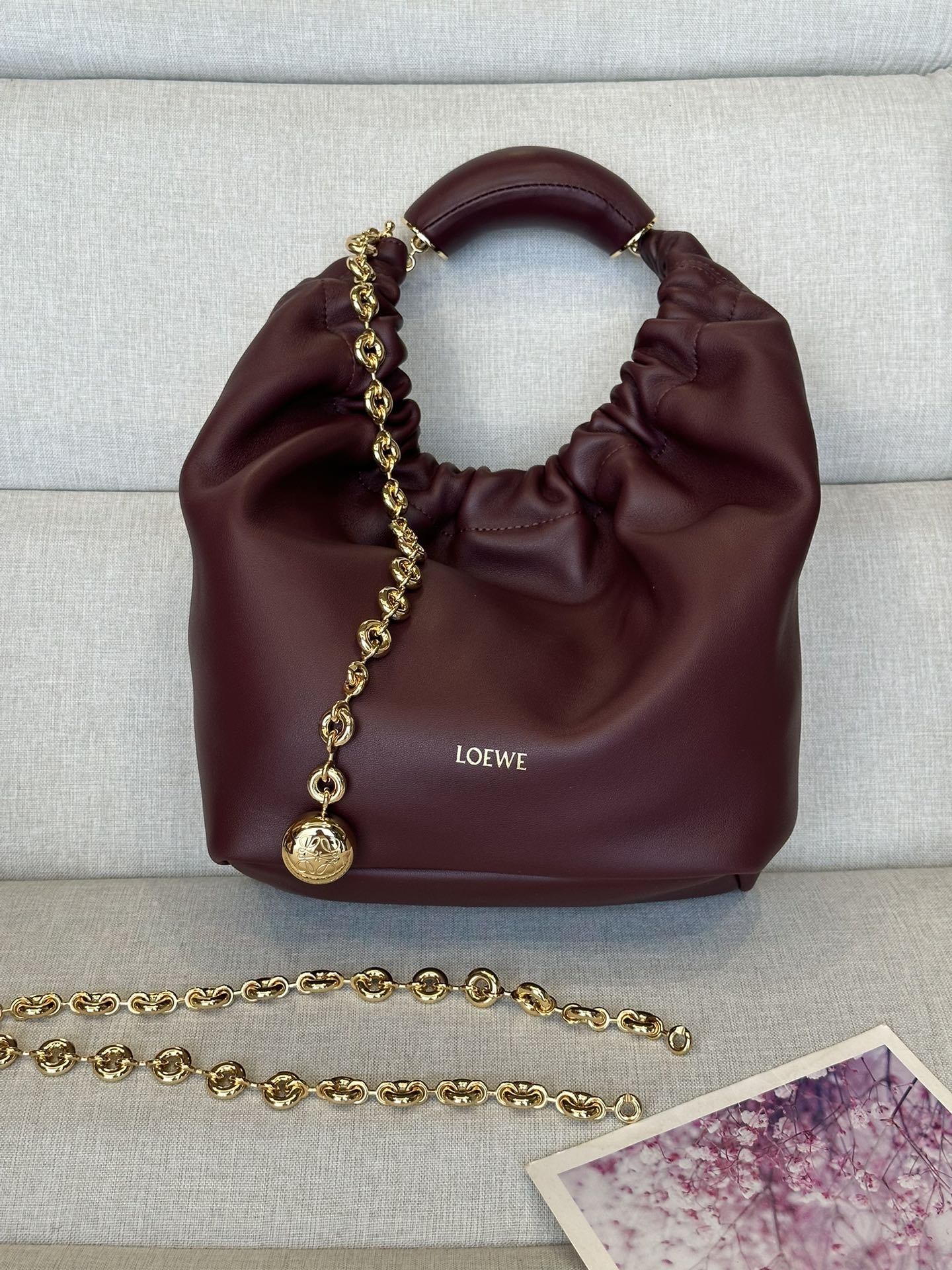 NO:179442,LOw Small Model 3901 Burgundy Napa Sheepskin Squeeze Handbag A new exquisite and soft handbag made of soft-touch Napa leather. This craft is a masterpiece of traditional craftsmanship, innovative research and unique design, with a surprisingly lightweight pleated body, adjustable donut chain and soft handle. This trumpet is made of Napa Sheepskin.* shoulder-mounted, cross-body or hand-held* adjustable chain straps, paired with Anagram carved pebbles, additional chains for further extensions* magnetic buckle closure* internal zipper pocket* unlined*lo*ewe gold or silver hot. size29*10.5*24CM All-steel hardware, special grade Loewe, sheepskin19860909LOw小号 型號3901 酒紅色 纳帕羊皮Squeeze手袋一款精致而柔美的全新手袋,采用触感柔软的纳帕皮革制成.这款顺手艺是传统工艺、创新研究和独特设计的杰作,具备令人惊讶的轻盈褶皱包身、可调节甜甜圈链条和触感柔软的提手.此小号版本采用纳帕羊皮革打造.*可肩背、斜挎或手提*可调节链条肩带,搭配Anagram携刻鹅卵石,附加额外链条,可进一步延长肩带*磁扣开合*内部拉链口袋*无衬里*lo*ewe烫金或烫银. size29*10.5*24CM 全钢五金,特级罗意威,loewe,sheepskin,Bag