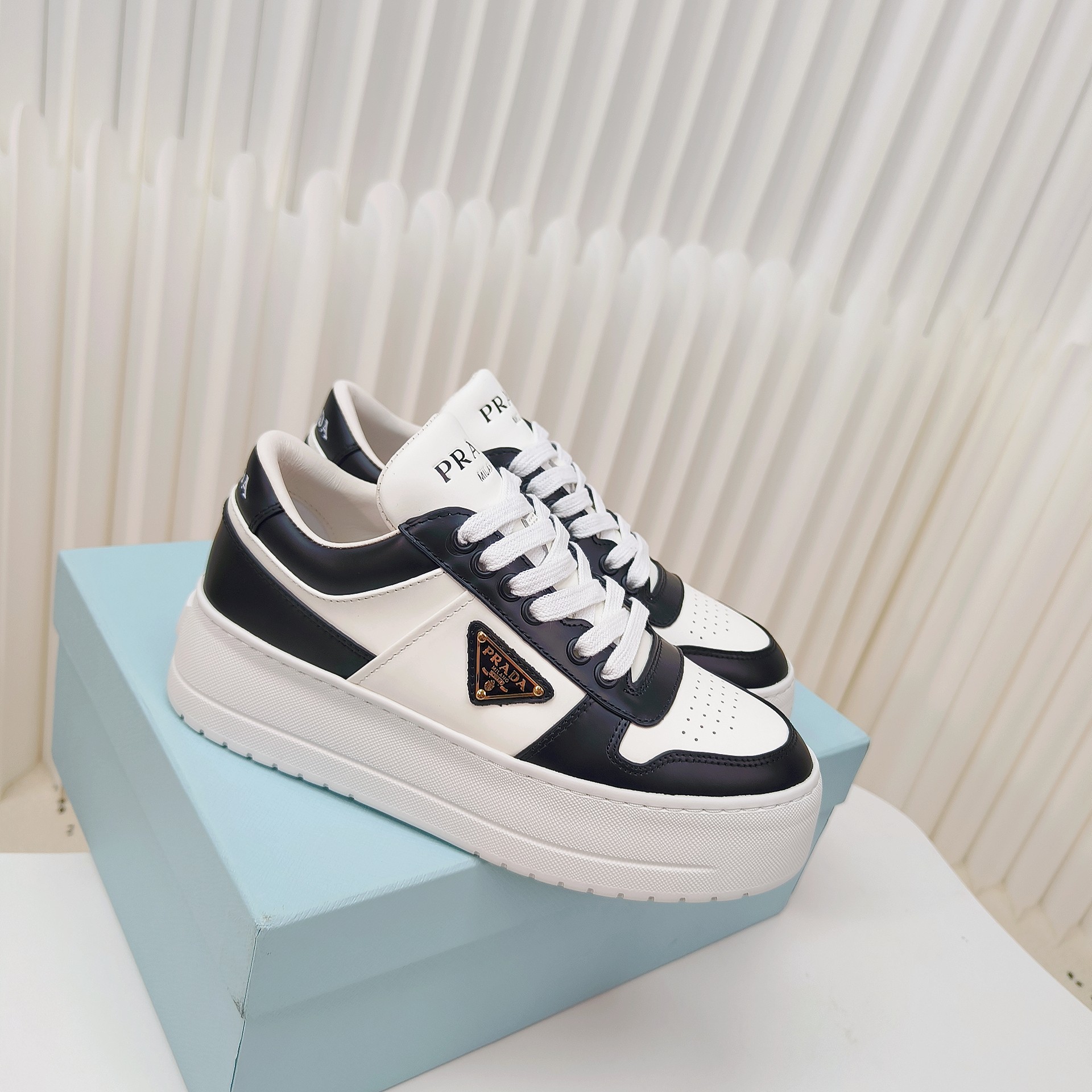 NO:562446,Prada Leather Sneakers Downtown Bold sneakers are inspired by basketball shoes from the 1980s, with a sporty design and refined details. Made of perforated leather, the statement platform gives a unique modern style. The Prada logo is interpreted from different angles and is decorated with the iconic enameled triangle metal logo, highlighting a unique classic style. ●Eye face ●Leather lining ●Enamel triangle metal logo ●Lace-up closure ●Rubber sole, 50 mm  ●Geometric pattern sole ●Removable leather insole ●Size 35-41 (40.41 customized), casual shoes/sports shoes, prada, prada, sneakers19860909Prada普拉达皮革运动鞋 Downtown Bold运动鞋从1980年代的篮球鞋汲取灵感,运动风设计搭配精致细节.采用穿孔皮革打造,个性的厚底呈现别具一格的现代风格.通过不同角度演绎Prada徽标,饰有标志性的涂珐琅三角形金属徽标,彰显别具一格的经典格调. ●鞋面孔眼 ●皮革衬里 ●涂珐琅三角形金属徽标 ●系带开合 ●橡胶鞋底,50毫米 ●几何纹路鞋底 ●可拆卸皮面鞋垫 ●码数35-41（40.41定做）,休闲鞋/运动鞋,prada,prada,sneakers,Women's Shoes