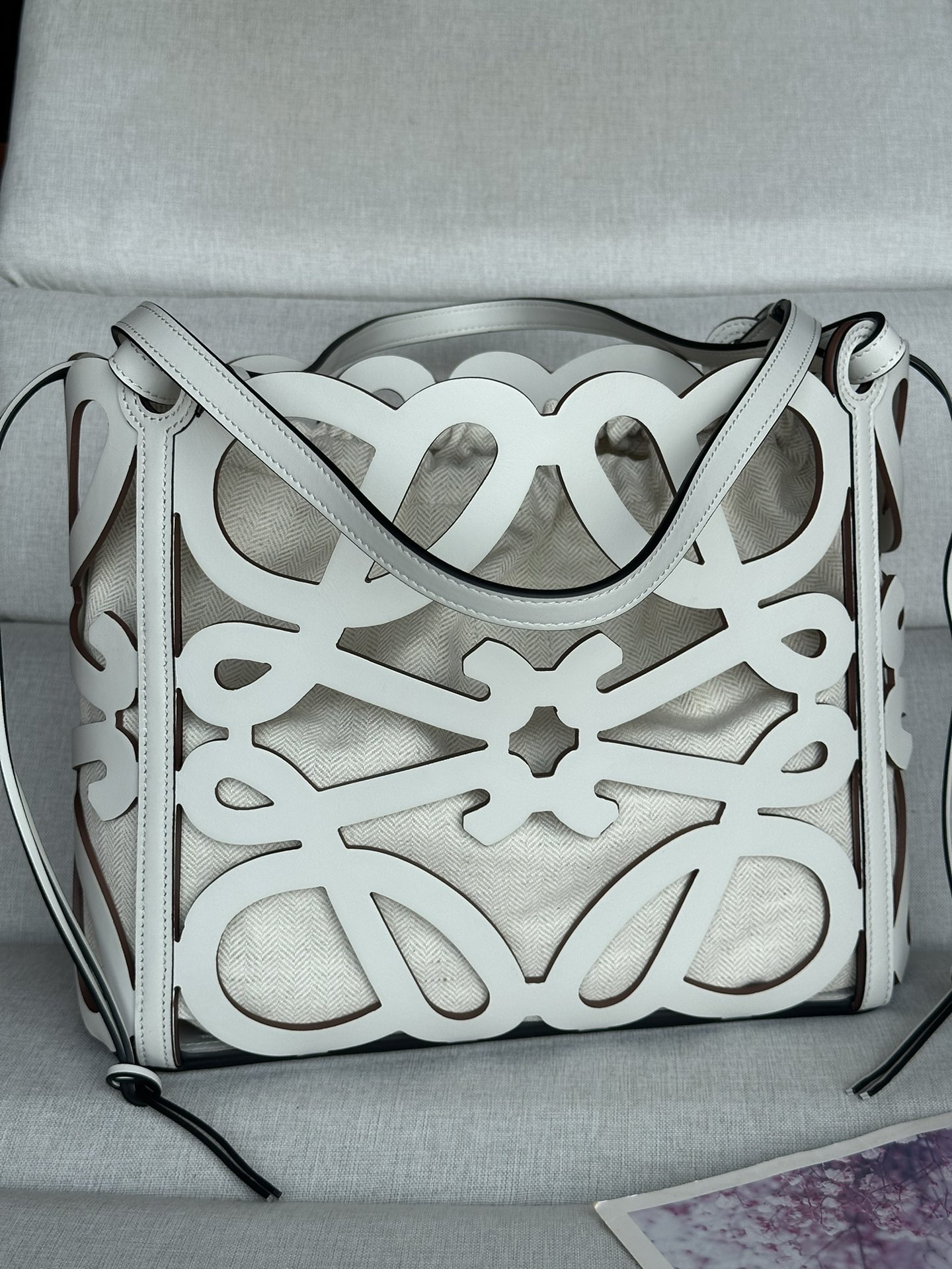 NO:181813,Cowhide leather hollow Anagram Tote handbag really grows on my aesthetics, with large hollow black logo, built-in linen inner bag, and thin ropes that can be retracted on both sides. The armpit back is not a problem at all. Cool and cool. This multi-functional, versatile casual capacity is touching and also has a fashionable Tote handbag made of Anagram pattern hollow cowhide leather, and is equipped with cowhide leather handles and herringbone cotton canvas belt inner bag. This version is small-sized version. There are no more or less. The fashionable L0EWE hollow bag has two colors for both practicality and appearance. After trying the back of the upper body, I chose brown hollow not to pick the season. The main thing is to fit the clothes. Basically, everything you go out every day can be stuffed with the lower * shoulder or top handle to carry * cowhide leather drawstring. Size 32CM~27CM~11CM  Model number 10678 Color white, special grade Loewe, cowhide19860909牛皮革镂空 Anagram Tote 手袋真的长在我的审美上,镂空黑色大logo,内置麻质内袋,两边有可以收缩的细绳,腋下背完全不是问题酷帅酷帅,这款多功能 ,百搭休闲容量感人的同时还带着时尚感Tote 手袋采用 Anagram 图案镂空牛皮革制成,并配有牛皮革提手和人字形棉帆布束带内袋这个版本为小尺寸版本不多不少 时髦度刚刚好的L0EWE镂空包一款实用性和颜值兼具的tote有两个配色,上身试背之后还是选择了棕色镂空不挑季节主要是和衣服都能搭容量基本上日常出门的东西都能塞的下*肩挎或顶部提手携带*牛皮革抽绳 尺寸32CM~27CM~11CM 款号10678 颜色白色,特级罗意威,loewe,cowhide,Bag