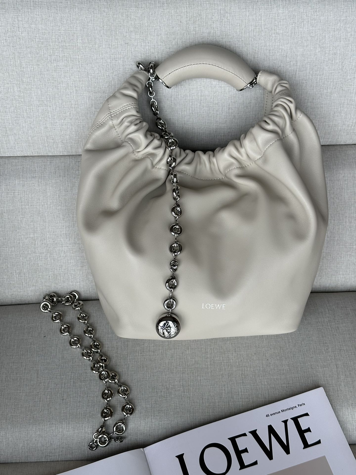 NO:182204,Genuine Grade Original Leather Version LOw Small Model 3901 Salt White Napa Sheepskin Squeeze Handbag A new exquisite and soft handbag made of soft-touch Napa leather. This craft is a masterpiece of traditional craftsmanship, innovative research and unique design, with a surprisingly lightweight pleated body, adjustable donut chain and soft handle. This trumpet version is made of Napa Sheepskin.* shoulder-mounted, cross-body or hand-held* adjustable chain straps, paired with Anagram carved pebbles, additional chains for further extension of shoulder straps* magnetic buckle closure* internal zipper pocket* unlined*lo*ewe gold or silver hot. size29*10.5*24CM All-steel hardware, special grade Loewe, sheepskin19860909正品级 原厂皮版本 LOw小号 型號3901 盐白 纳帕羊皮Squeeze手袋一款精致而柔美的全新手袋,采用触感柔软的纳帕皮革制成.这款顺手艺是传统工艺、创新研究和独特设计的杰作,具备令人惊讶的轻盈褶皱包身、可调节甜甜圈链条和触感柔软的提手.此小号版本采用纳帕羊皮革打造.*可肩背、斜挎或手提*可调节链条肩带,搭配Anagram携刻鹅卵石,附加额外链条,可进一步延长肩带*磁扣开合*内部拉链口袋*无衬里*lo*ewe烫金或烫银. size29*10.5*24CM 全钢五金,特级罗意威,loewe,sheepskin,Bag