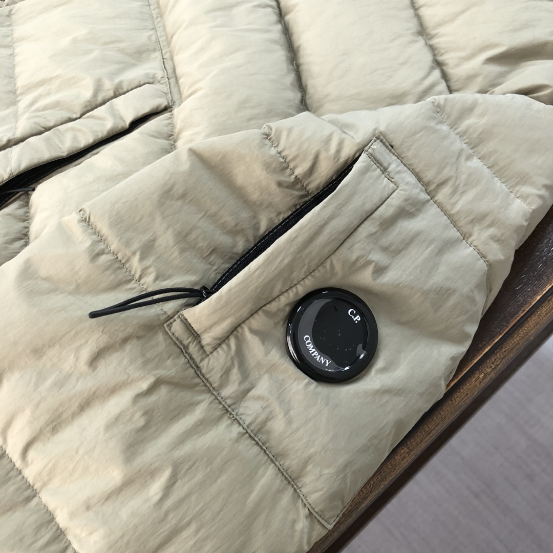 p565.00 CP.COMPANY 新款专柜同步，CP经典羽绒服，90进口羽绒 特殊高密记忆面料原厂染色防水，具备透气且防风功能 上身体感保温舒适度极好  简洁大方的设计 深受户外旅游爱好人士偏爱 也适合平时商务穿着的百搭款 所有辅料原版定制 实物拍照 现货供应  
颜色：黑色 卡其色 橘色
尺码：M-L-XL-XXL

