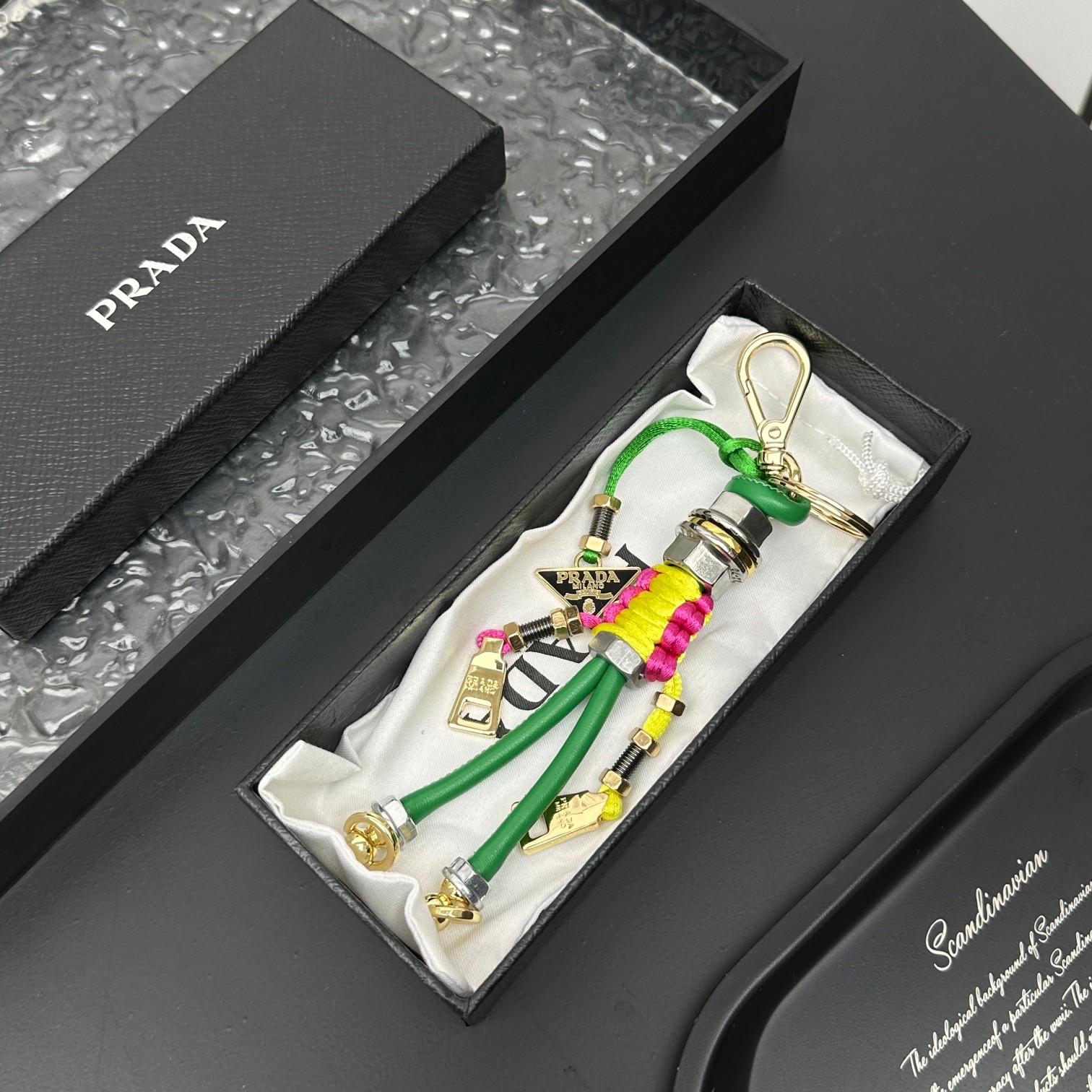 新款🌟这款钥匙扣呈现 Saffiano 牛皮革手工编织富有辨识度的十字纹理，饰有标志性的涂珐琅金属徽标。