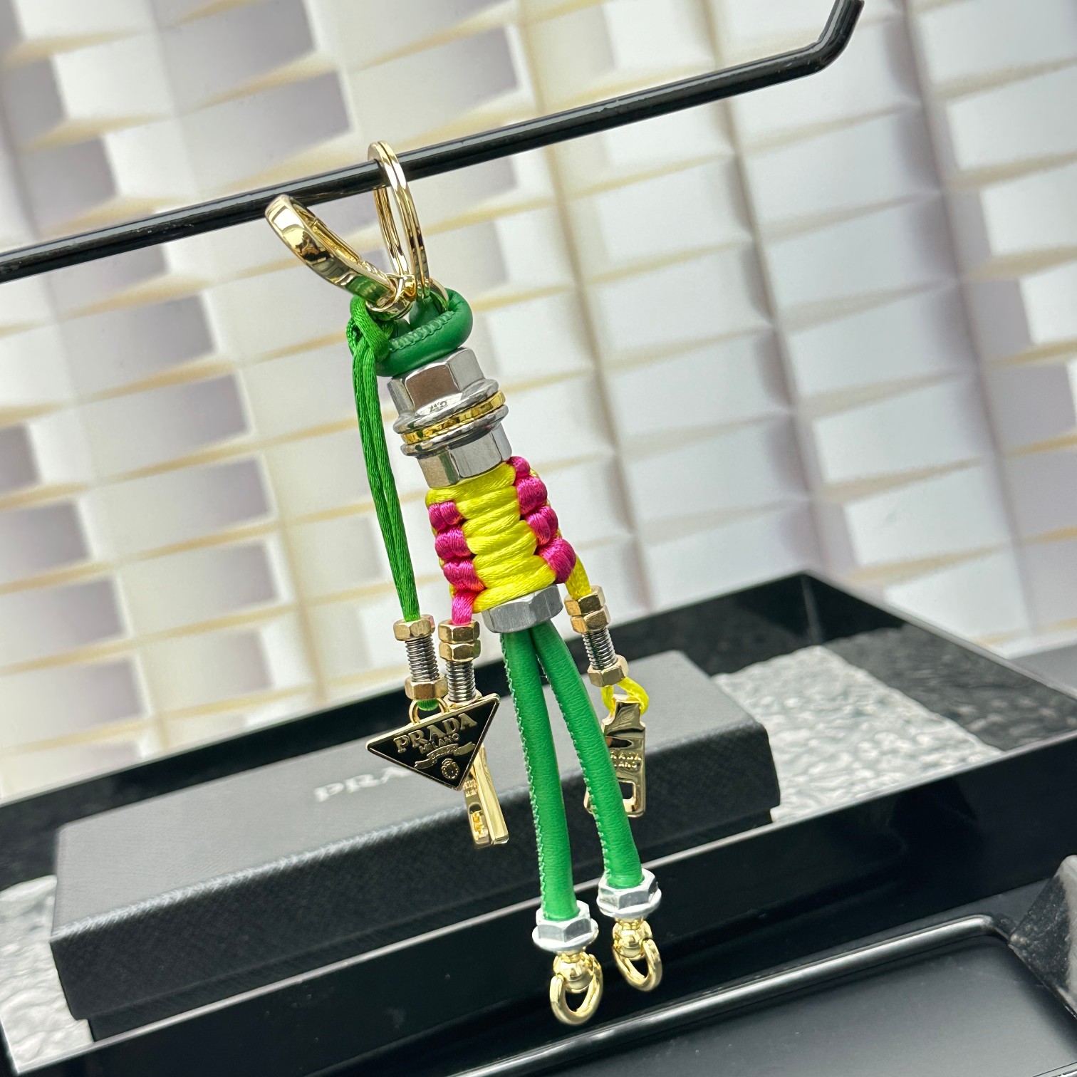 新款🌟这款钥匙扣呈现 Saffiano 牛皮革手工编织富有辨识度的十字纹理，饰有标志性的涂珐琅金属徽标。