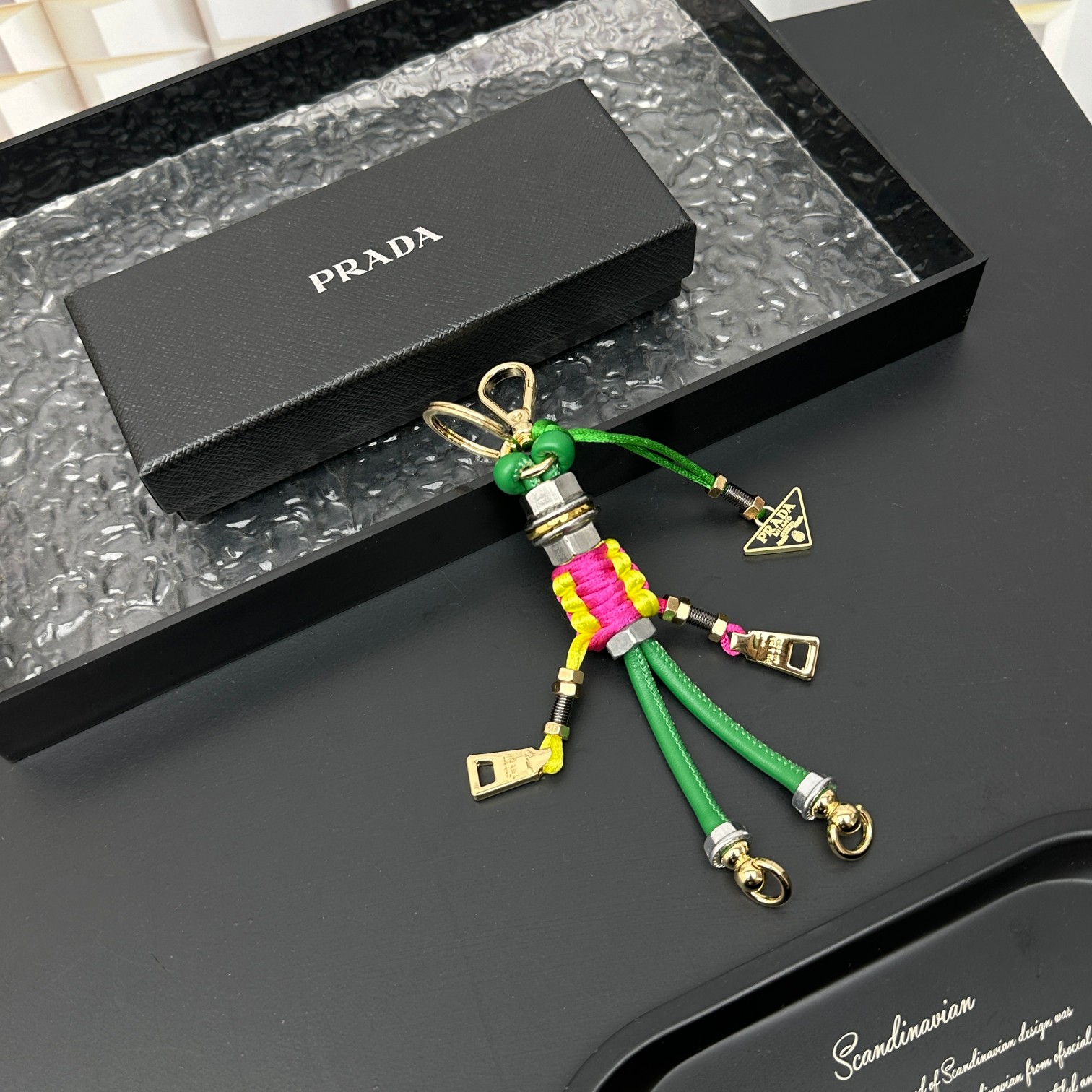 新款🌟这款钥匙扣呈现 Saffiano 牛皮革手工编织富有辨识度的十字纹理，饰有标志性的涂珐琅金属徽标。