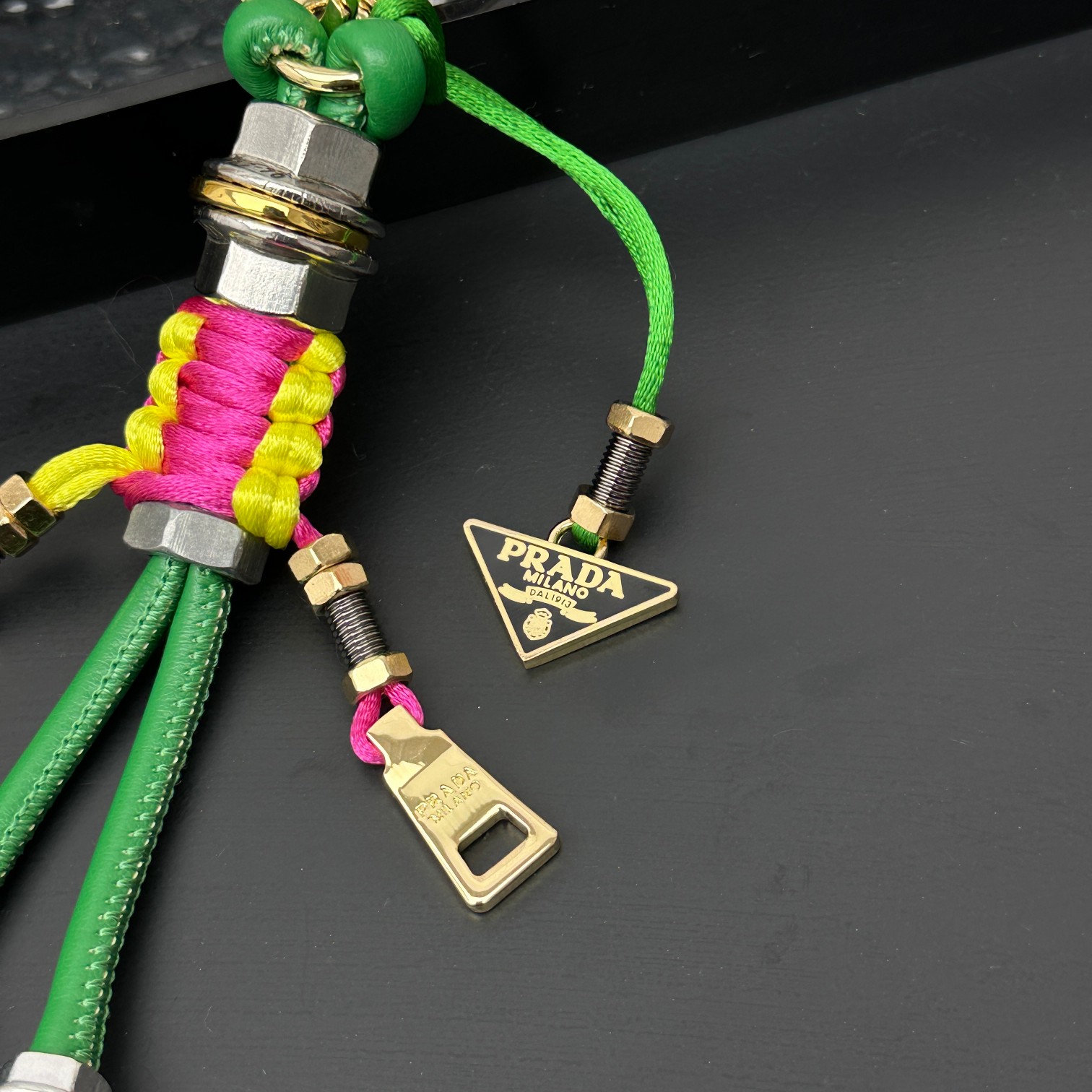 新款🌟这款钥匙扣呈现 Saffiano 牛皮革手工编织富有辨识度的十字纹理，饰有标志性的涂珐琅金属徽标。