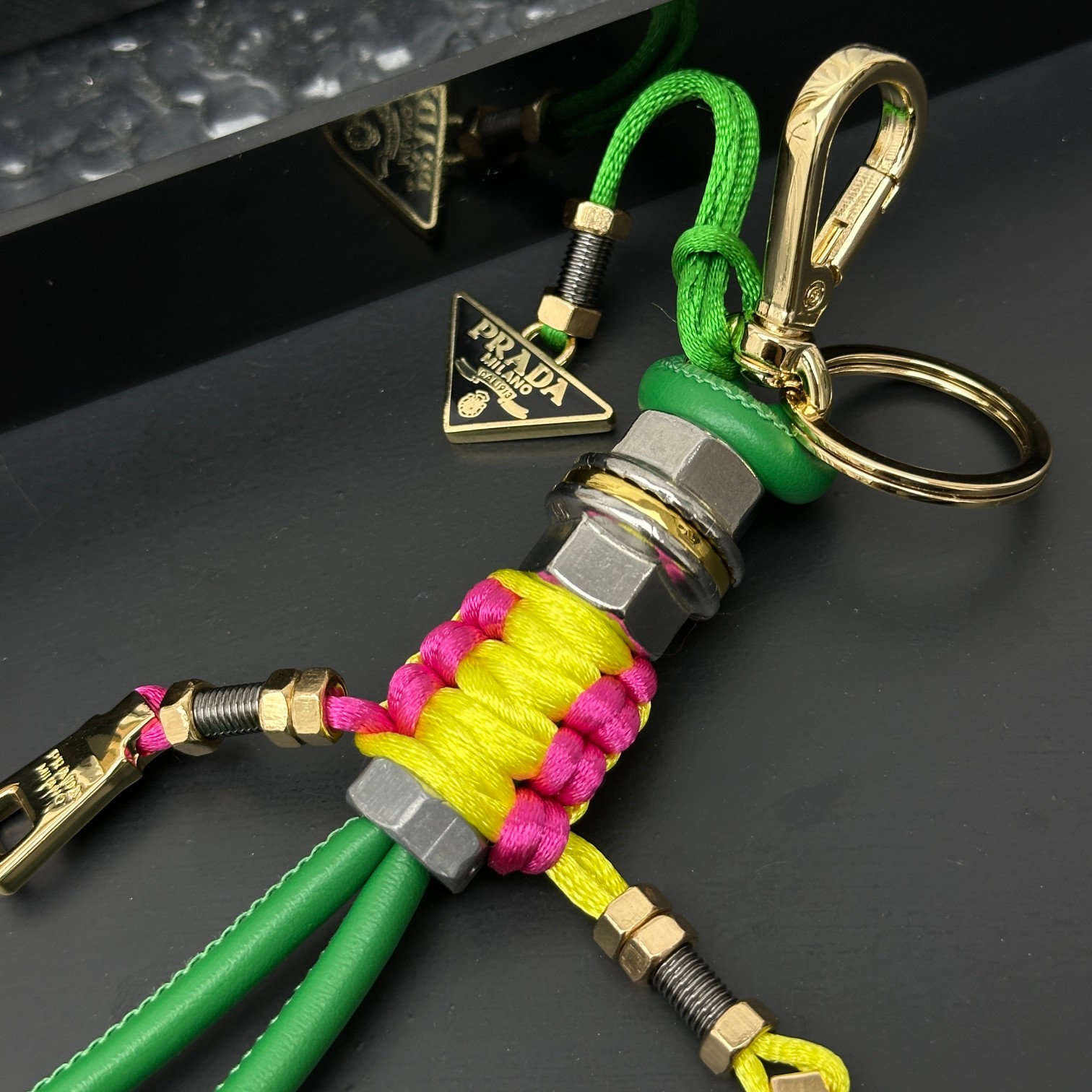 新款🌟这款钥匙扣呈现 Saffiano 牛皮革手工编织富有辨识度的十字纹理，饰有标志性的涂珐琅金属徽标。